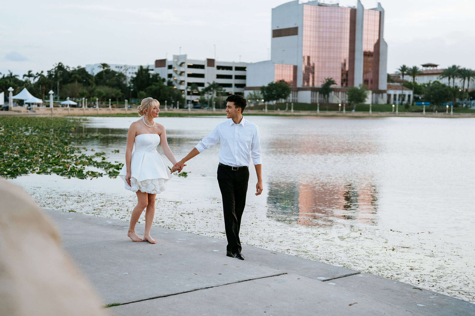  bride and groom walking along Lake Mirror- Lakeland Fl wedding venue magnolia building at Lake Mirror