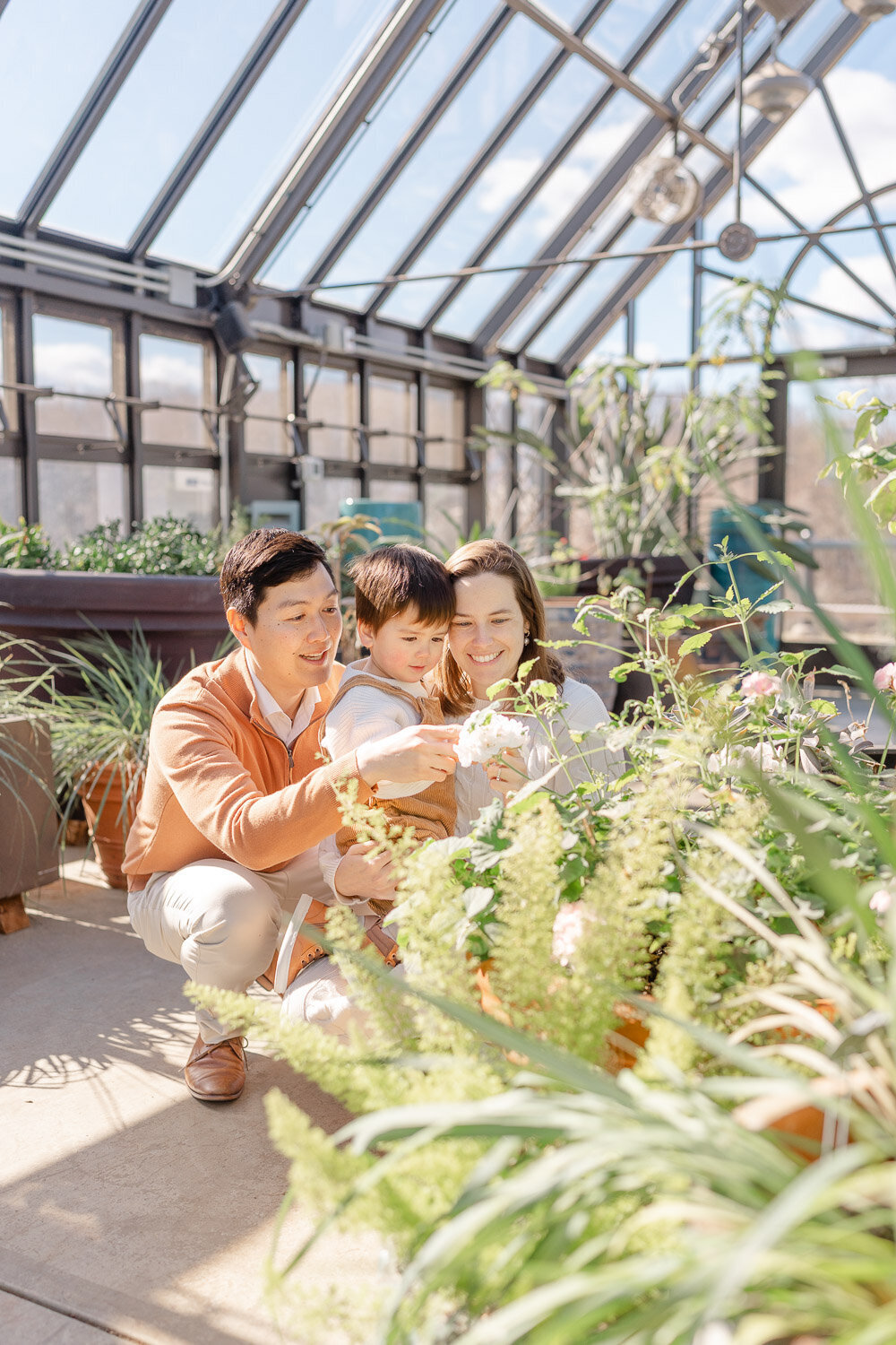 family looking at flowers during maternity pictures in Reston, VA