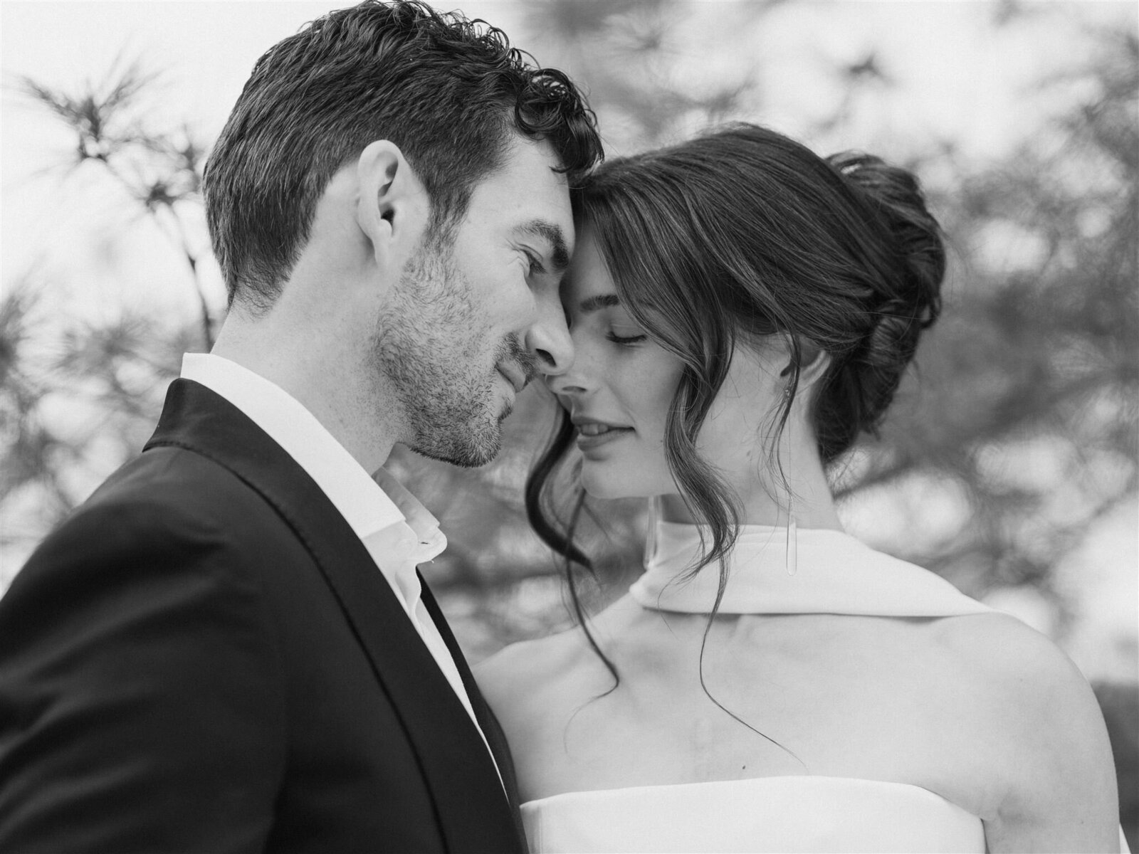 a Black & white image of a couple having a romantic moment with their foreheads together