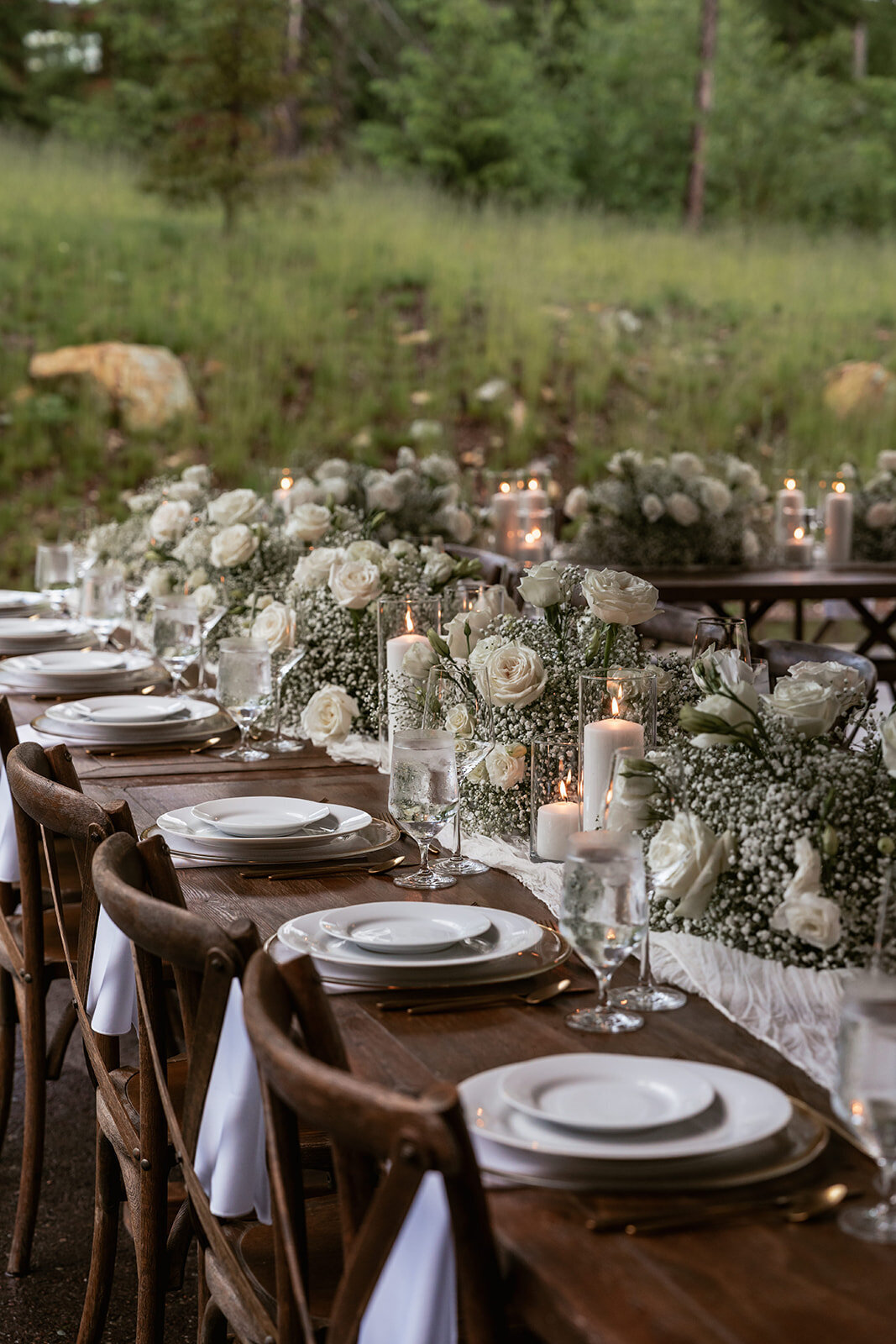 Refined elopement dinner table decorated with white roses, baby’s breath, candles, and linen runners, creating a romantic and timeless setting.