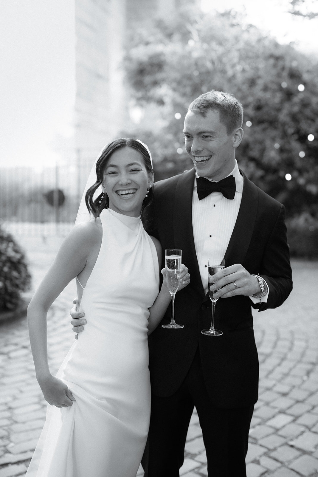 Bride and Groom laughing with champagne in NJ outside the wedding venue