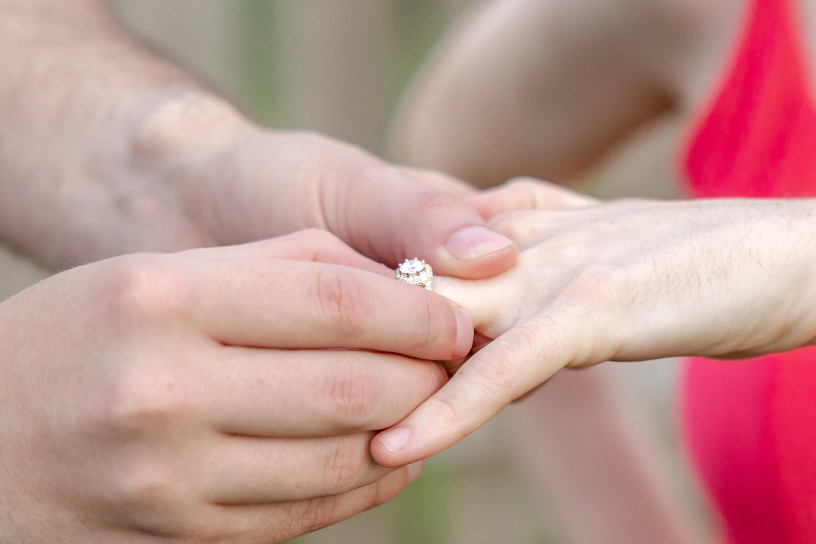 A close-up of a man gently placing an engagement ring on a woman's hand. The sparkling ring is the focal point, with soft natural lighting emphasizing the moment. This intimate detail captures the joy of engagement photography in North Carolina. 