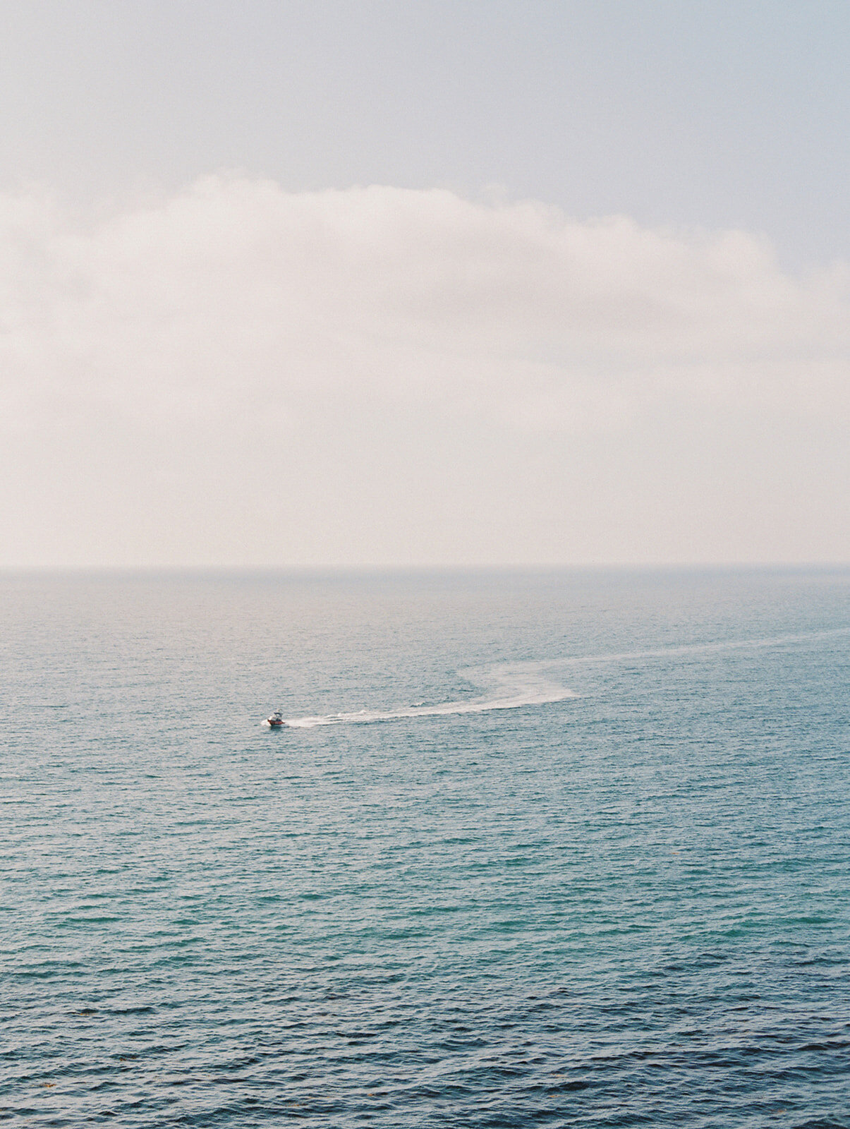Kohnur ocean horizon view from a coastal cliffside showing vast blue water and a distant boat.