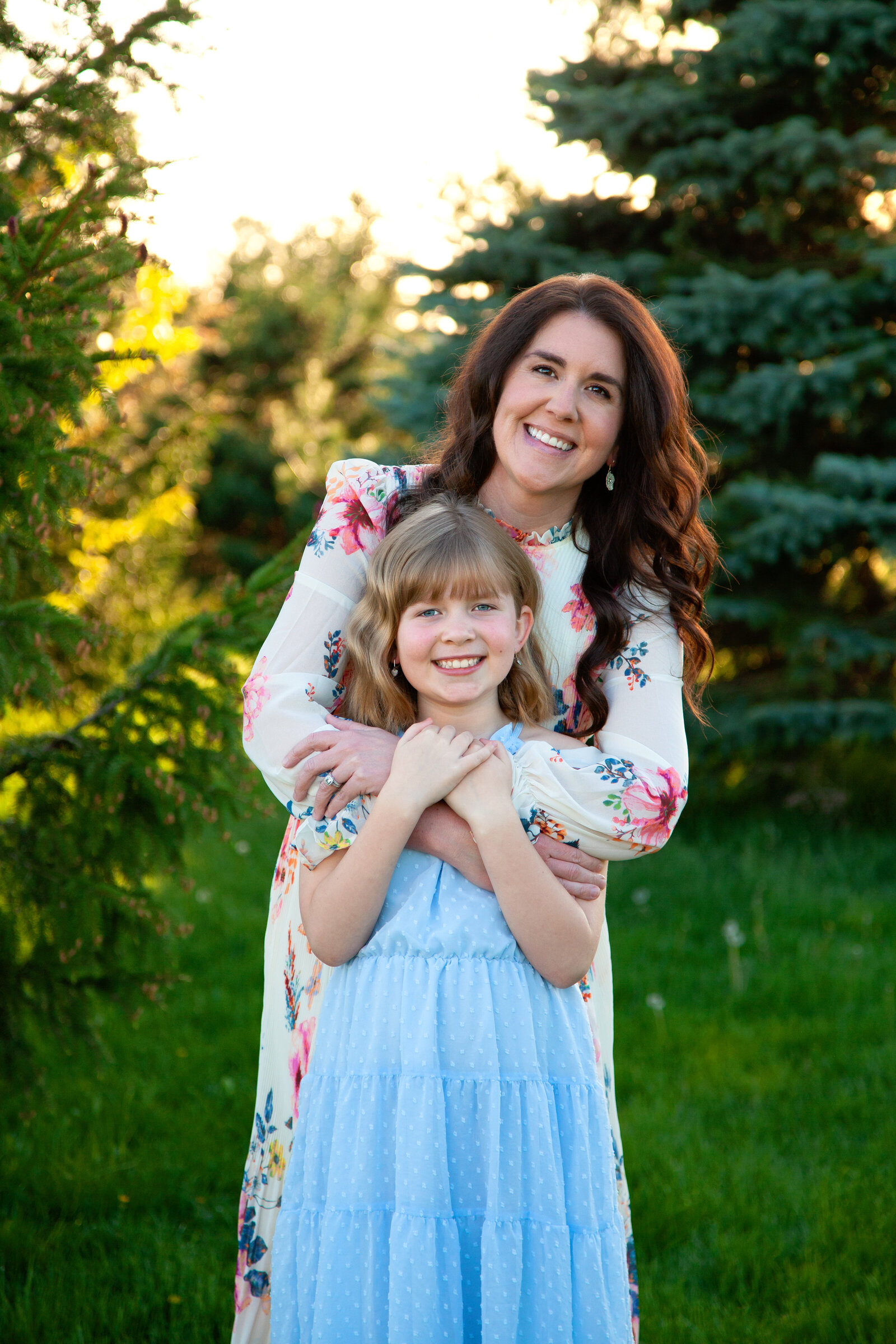 Mother hugging daughter around shoulders, both smiling.