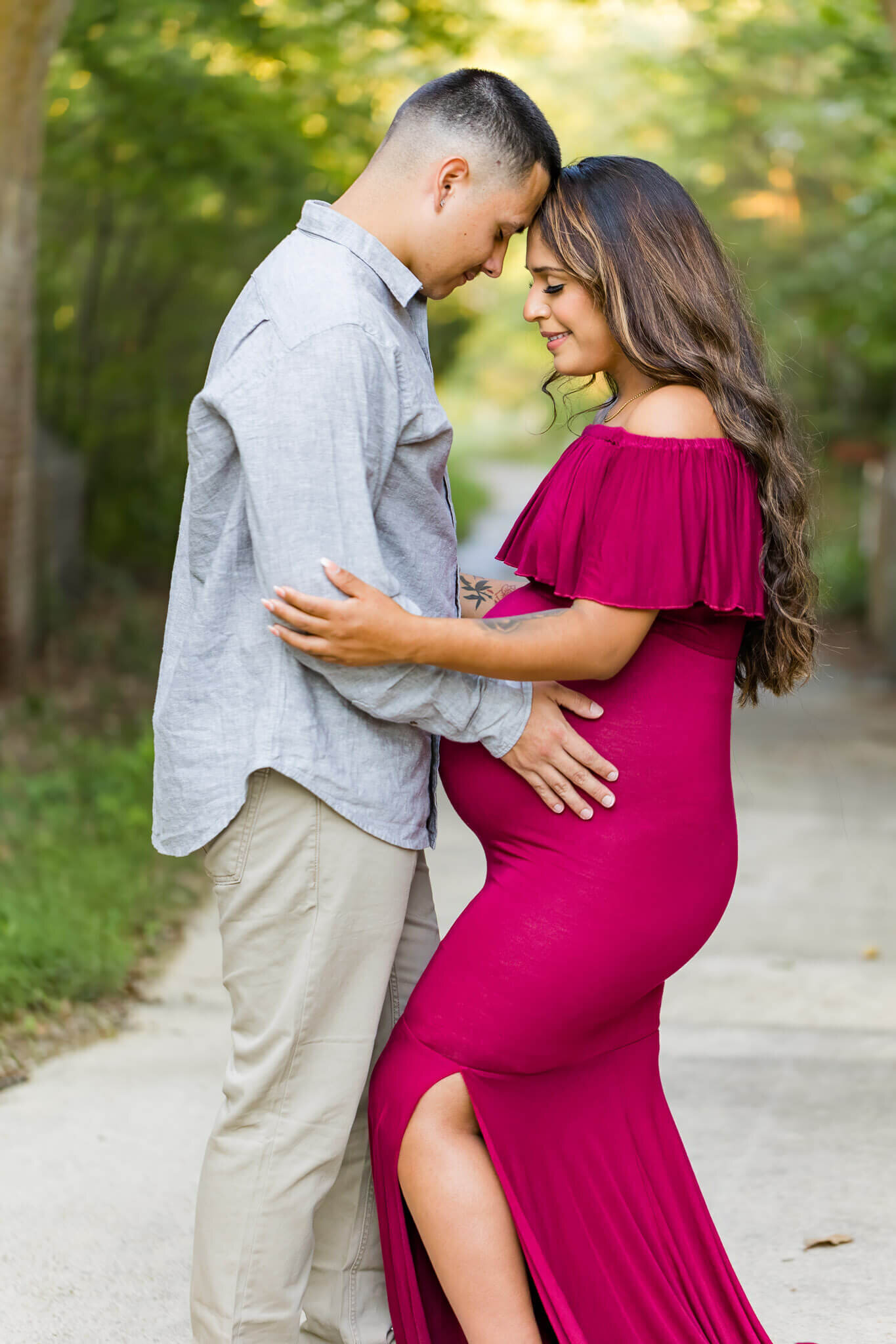 An expecting couple holding each other at a park in Lorton, VA.