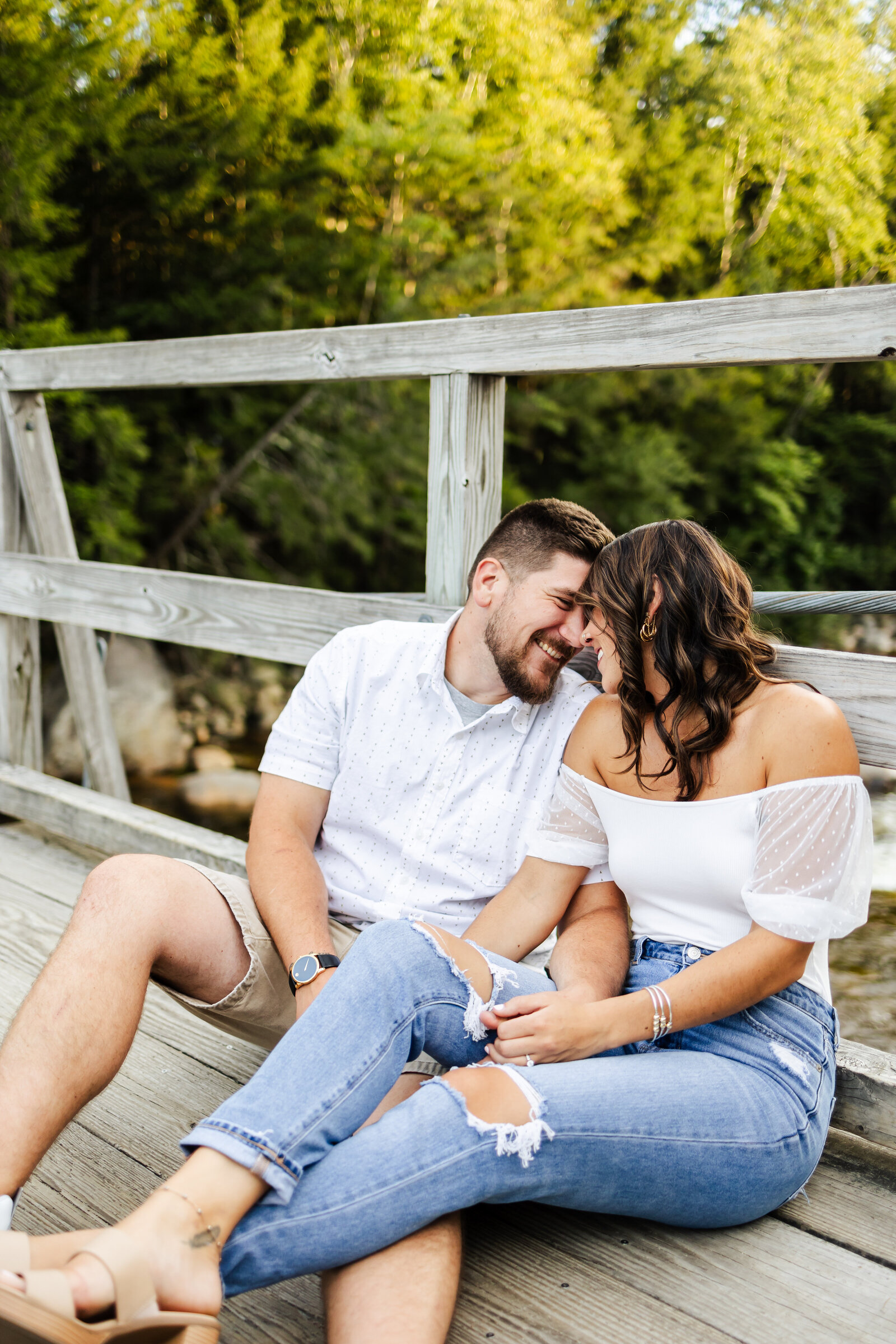 Bride and groom nuzzle in close and laugh during engagement session in Lincoln, New Hampshire