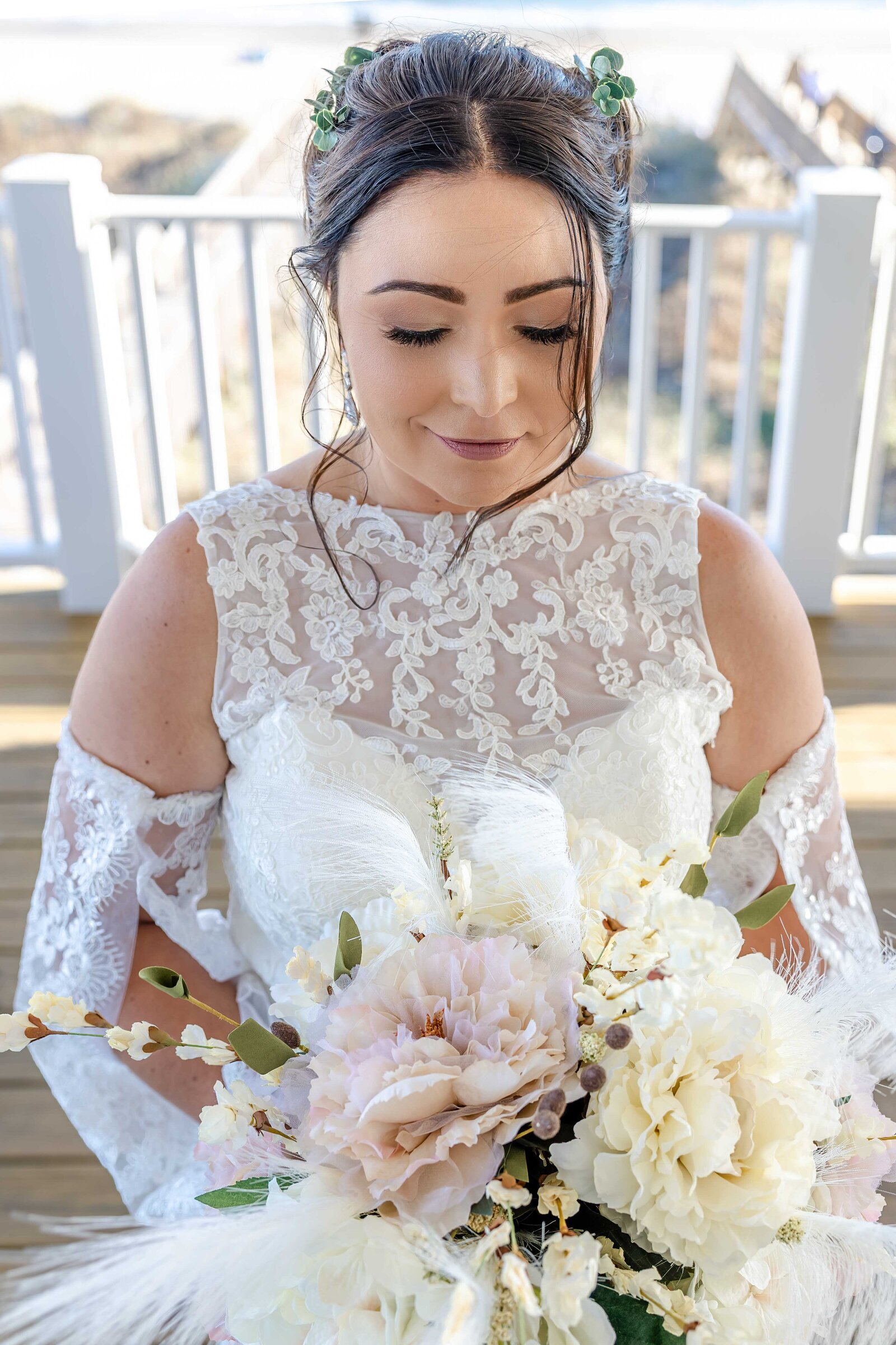 A stunning bridal portrait featuring the bride holding an elegant bouquet of white and blush flowers, captured at a wedding in Kure Beach, NC, with light and bright tones showcasing authentic beauty.