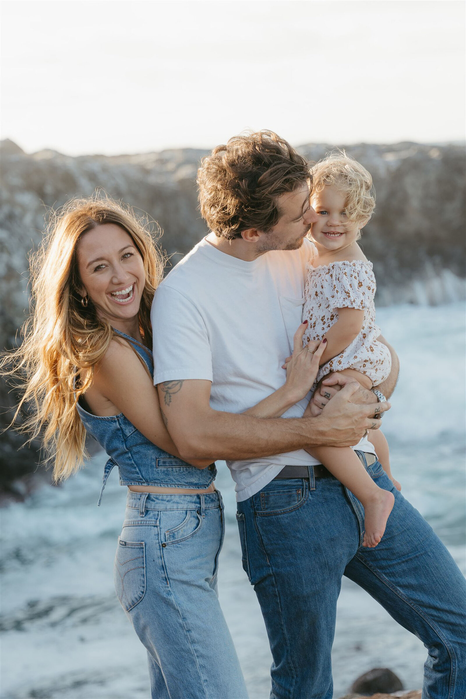 Together on a Maui cliffside at sunset, wearing denim and neutral outfits during an editorial family photography session.
