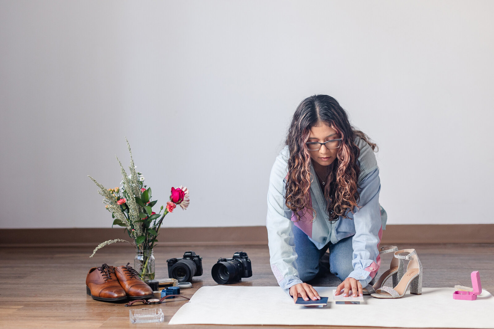 a wedding photographer arranges details for a flat lay photo