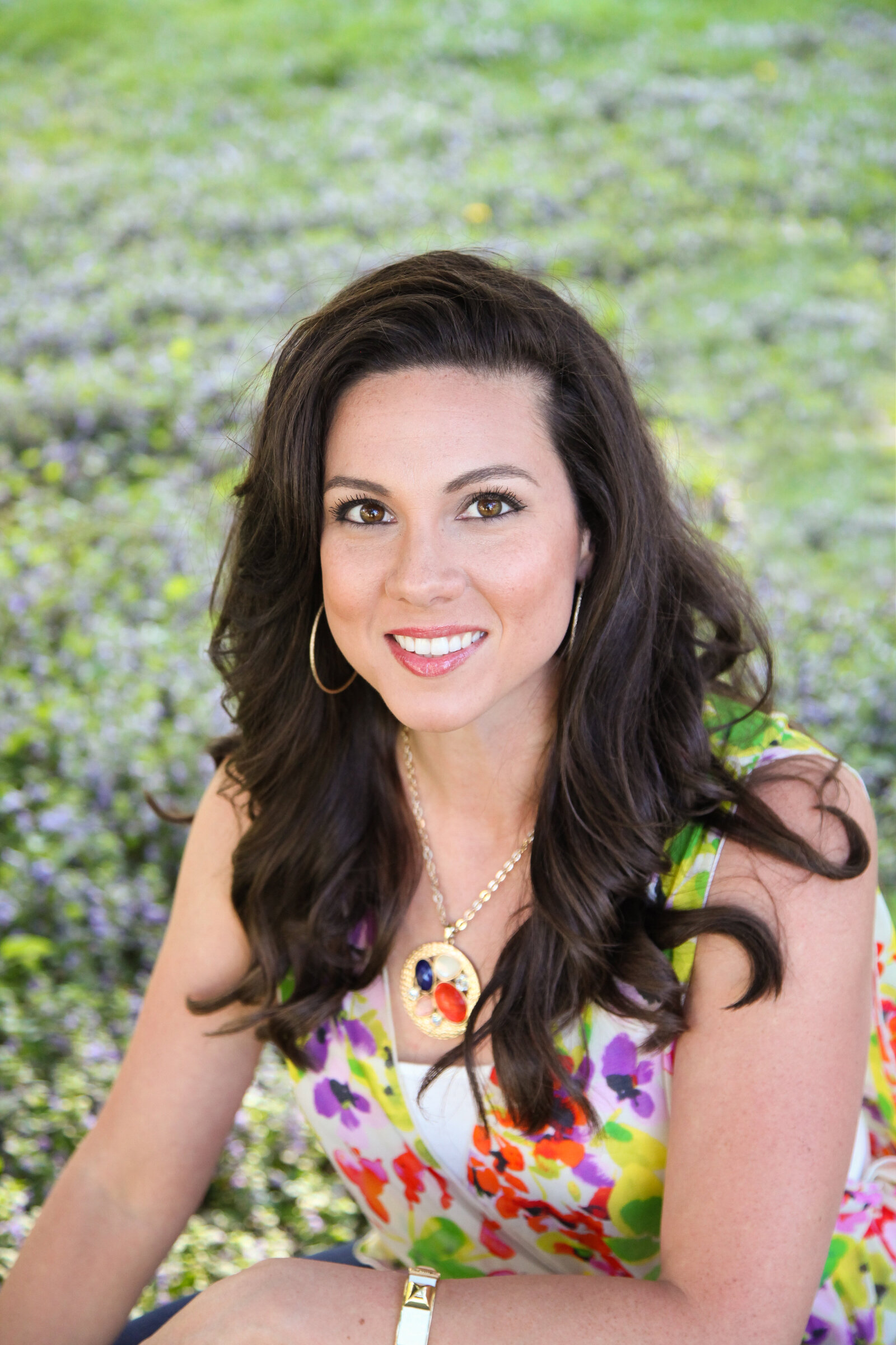Woman with long dark hair smiling at camea.