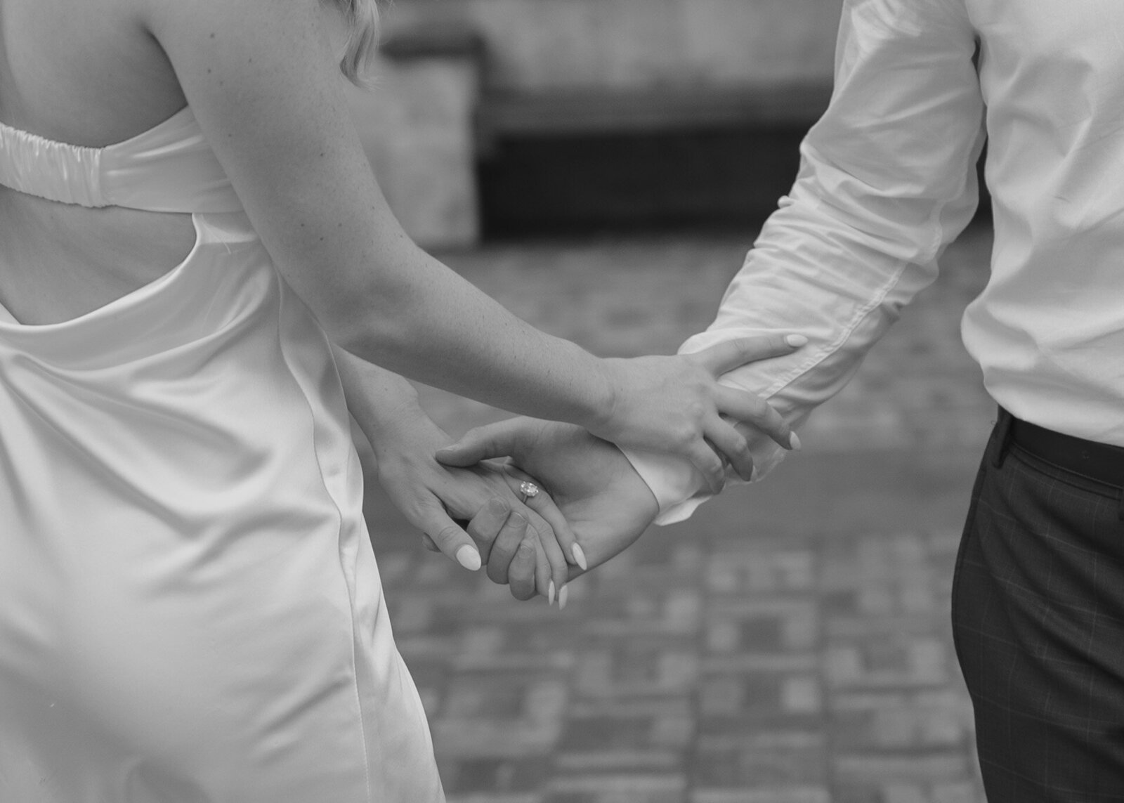 Black and white image of the bride and groom holding hands outside of their wedding venue in New York | Emma LeeAnn Photography