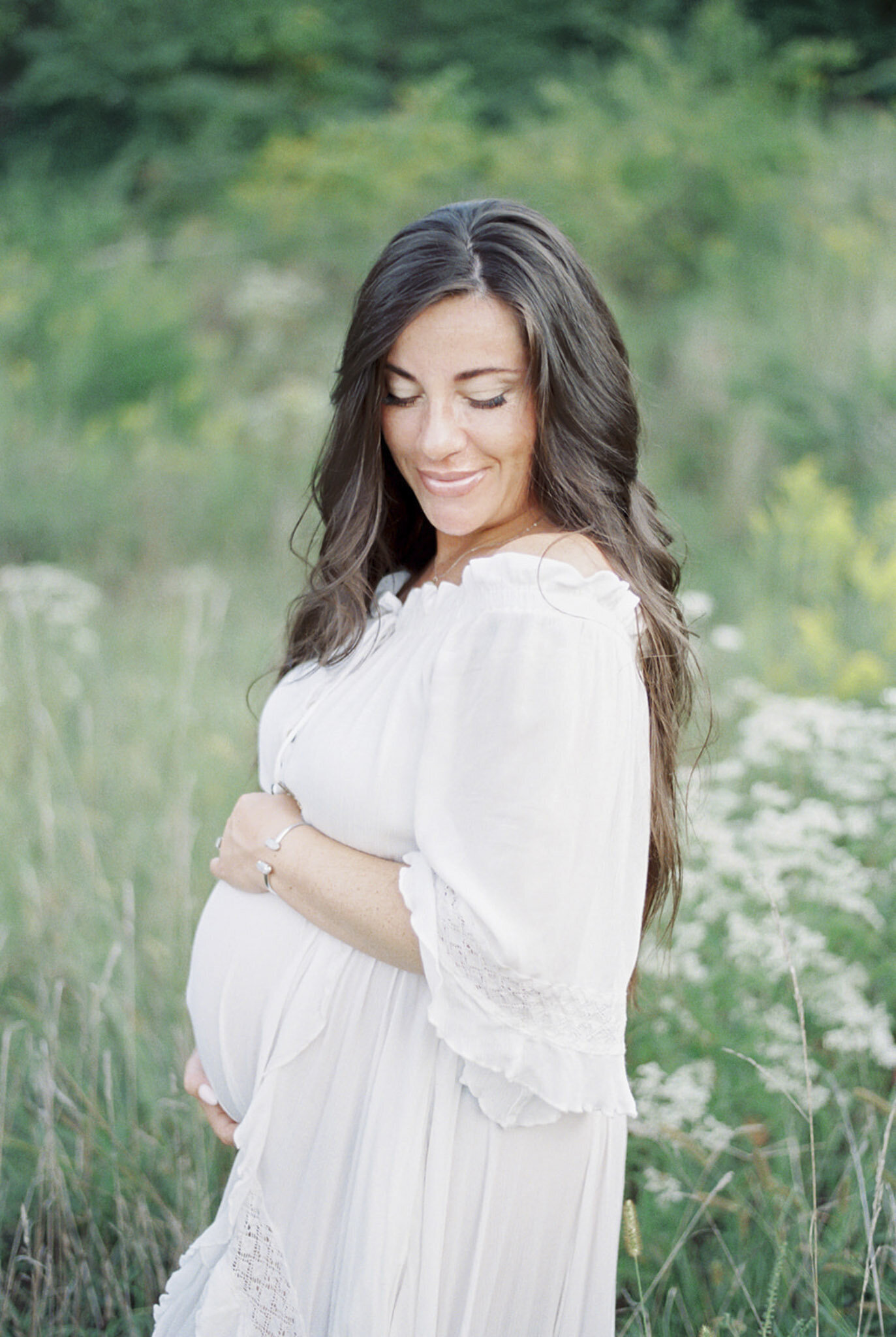 Pregnant woman in white dress with green grass behind her