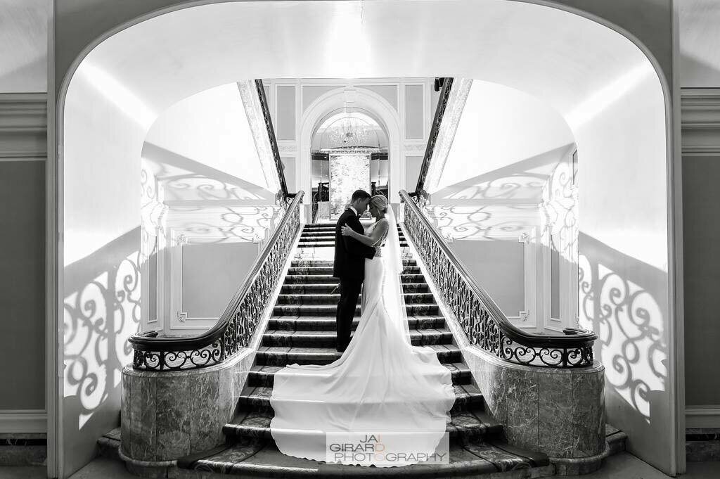 Bride and groom embrace on grand staircase