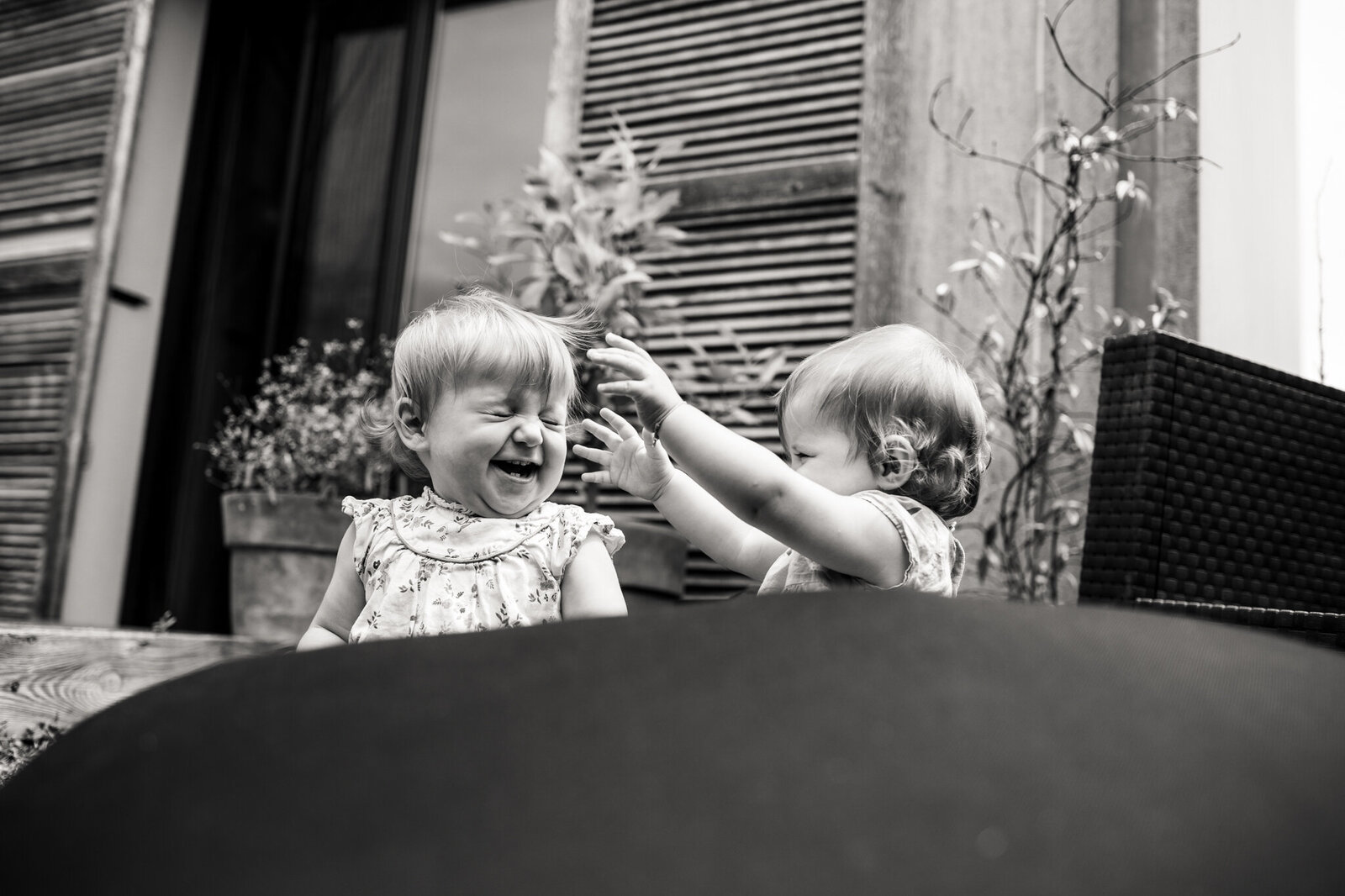 Twin babies playing together in the garden on a cushion