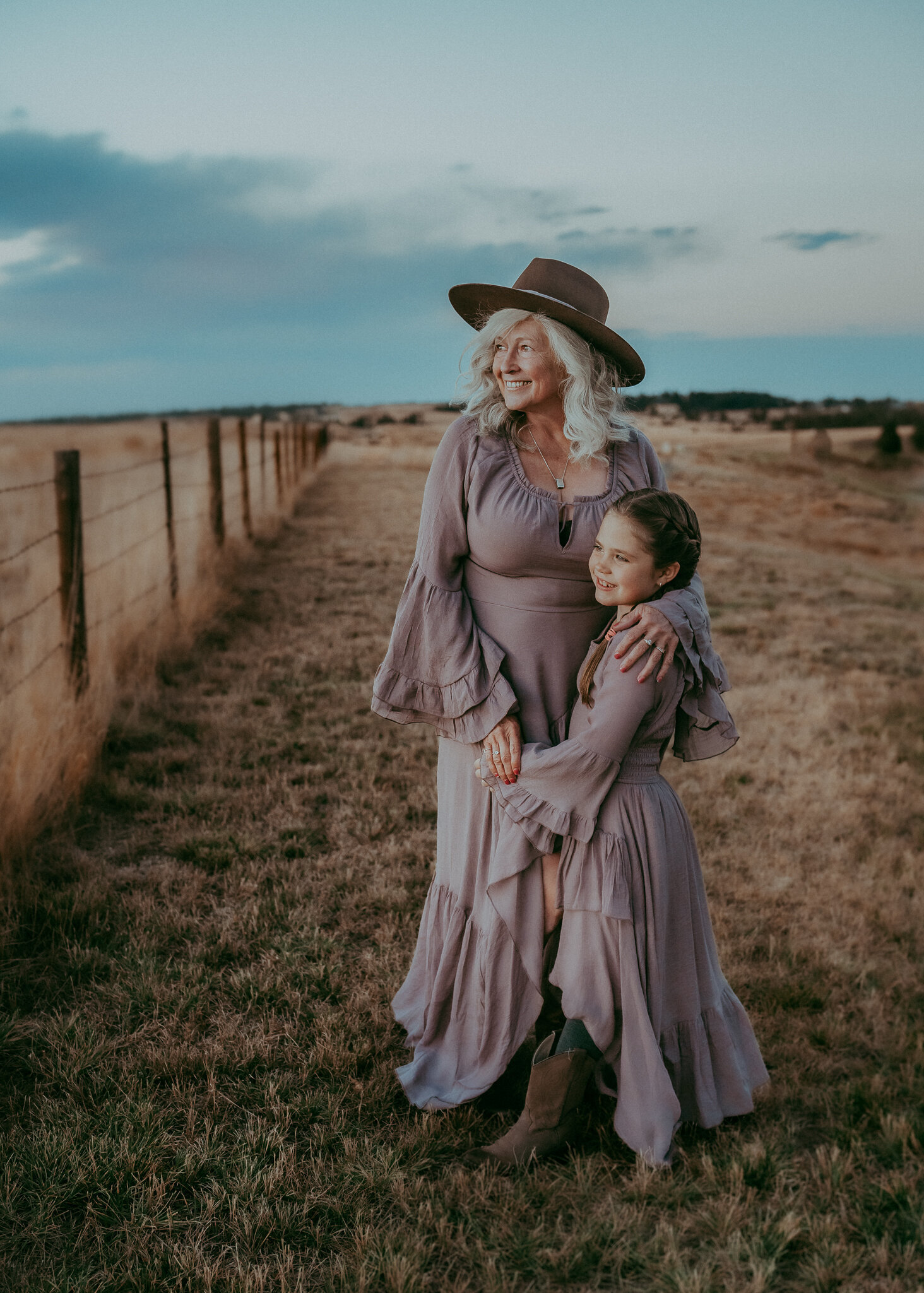 A grandmother, her granddaughter, as they wear matching Boho dresses in a stylized western photo session.