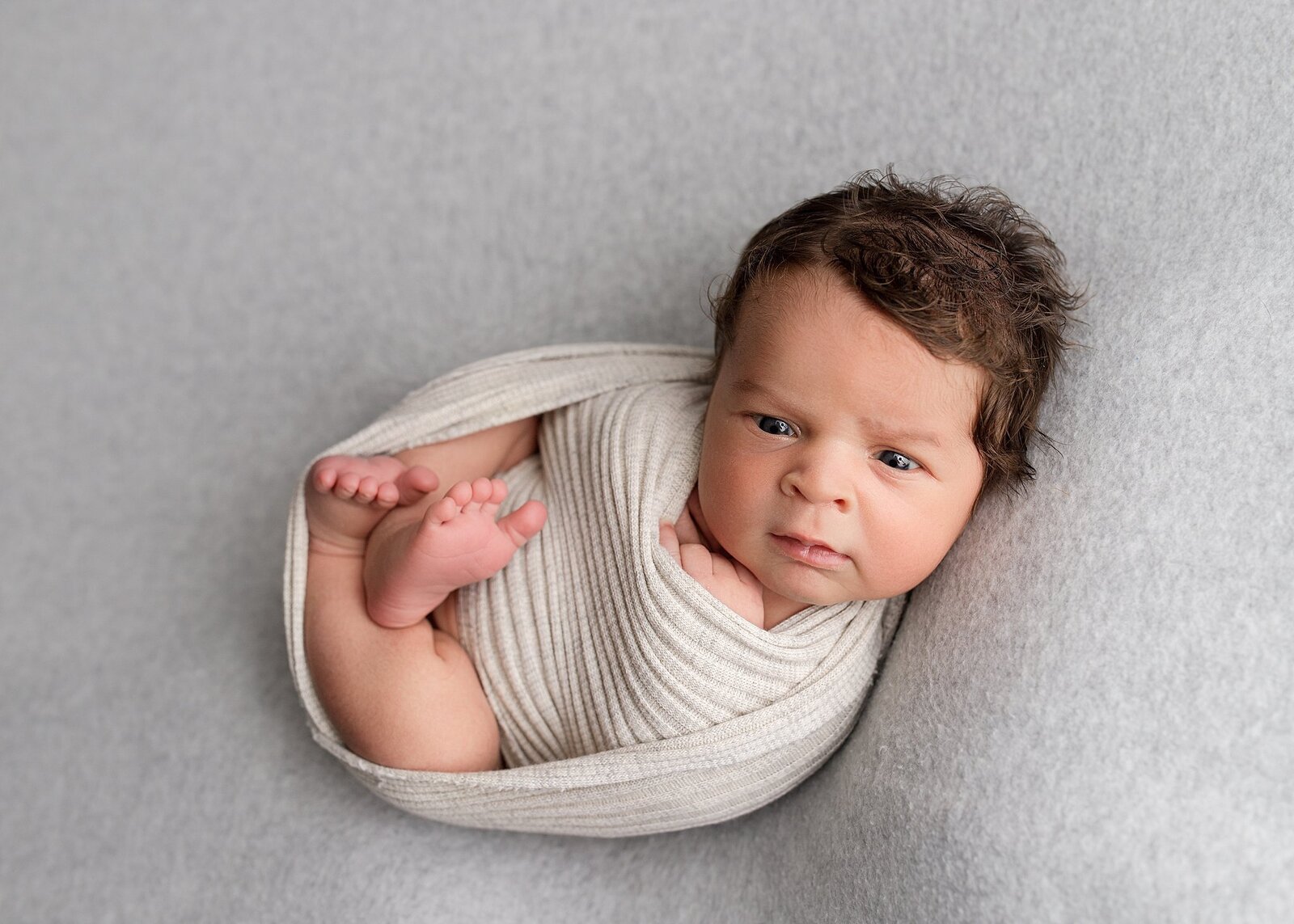 A newborn baby boy In bettendorf professionally  wrapped, posed and photographed in the quad cities