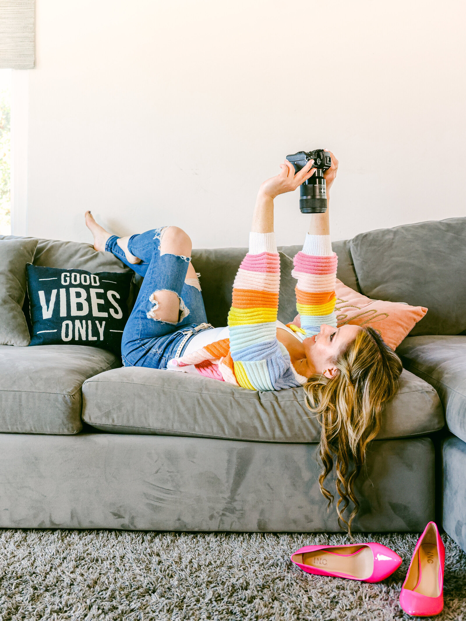 Girl sitting on couch taking selfie colorful sweater