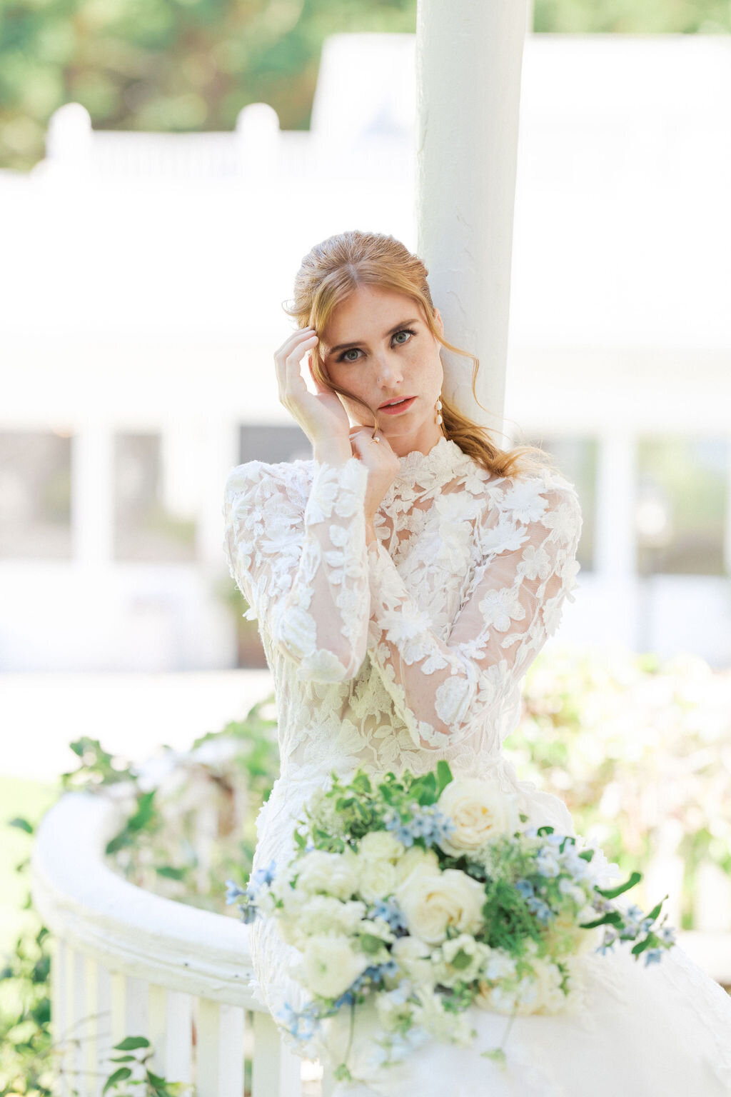 Bride with blue bouquet and lace dress stands outside the Wildflower Venue