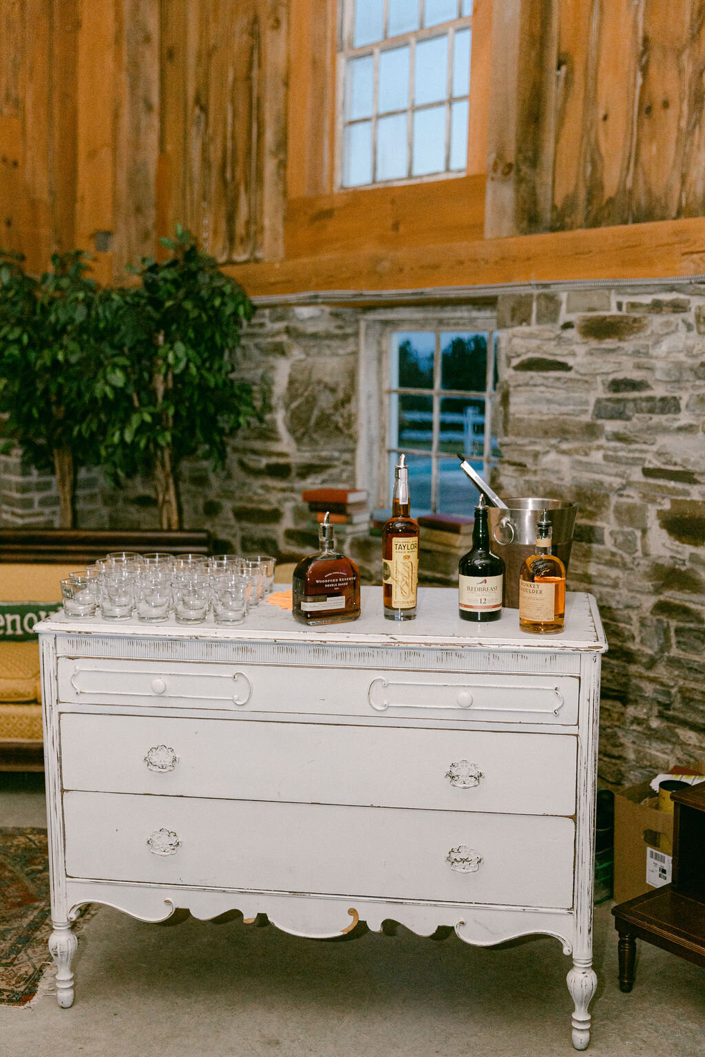 white dresser in stone barn holds a whiskey bar in Upstate