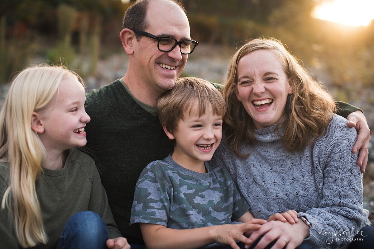 Family of four sitting by the river with gorgeous backlight during Seattle family photography session