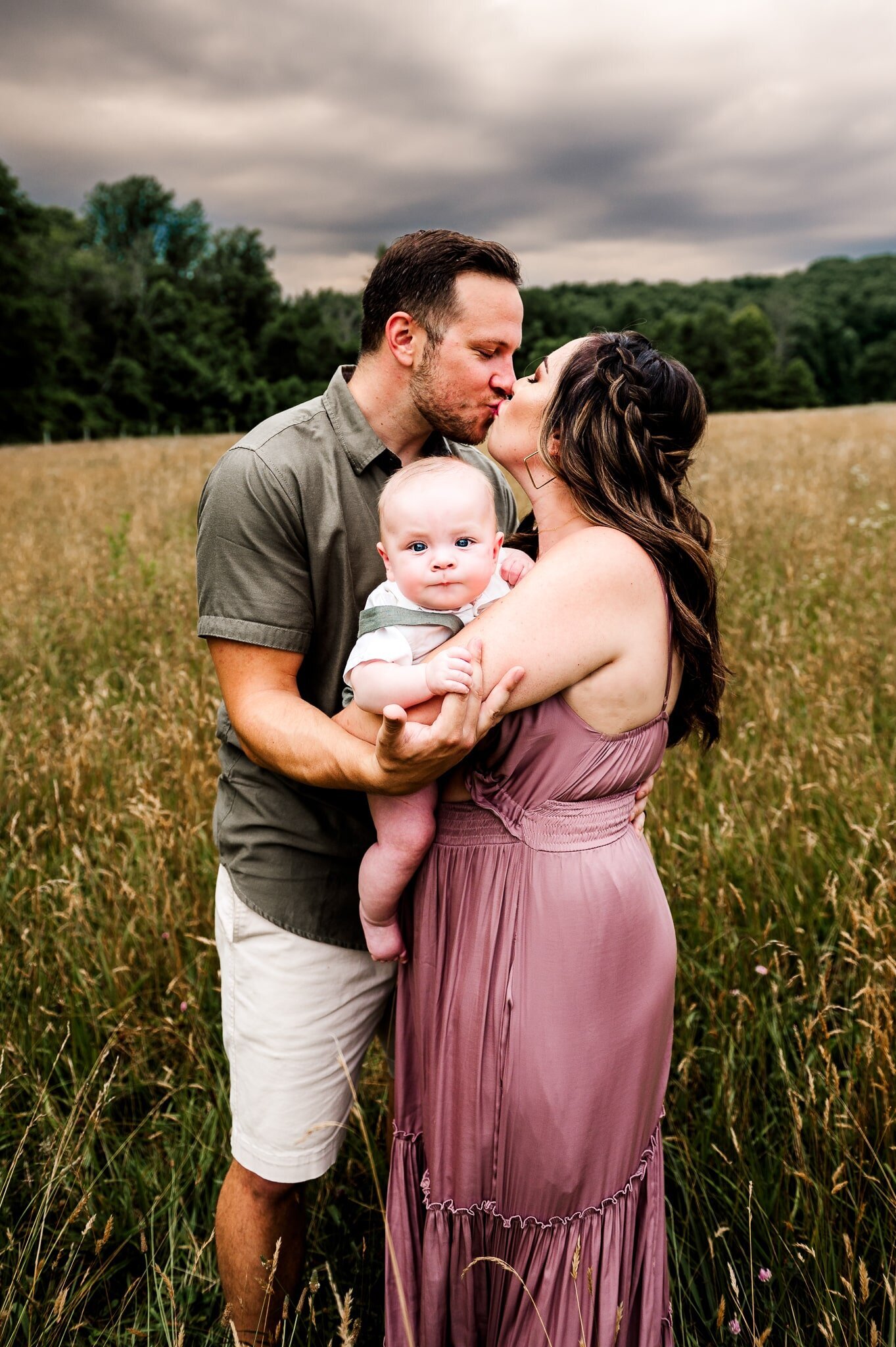 parents kissing for a picture while holding their son