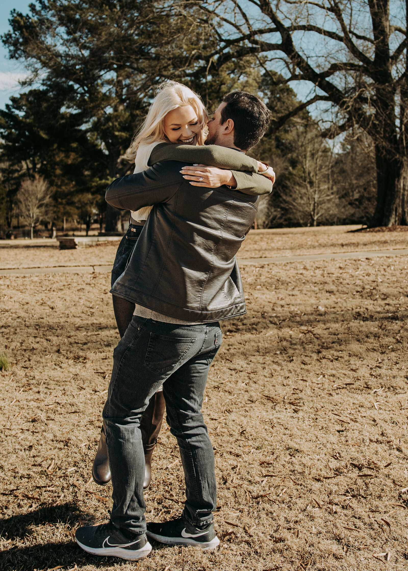 Rachel and Blaine embracing in a field during their engagement session in Oxford, Mississippi, sharing a romantic moment.