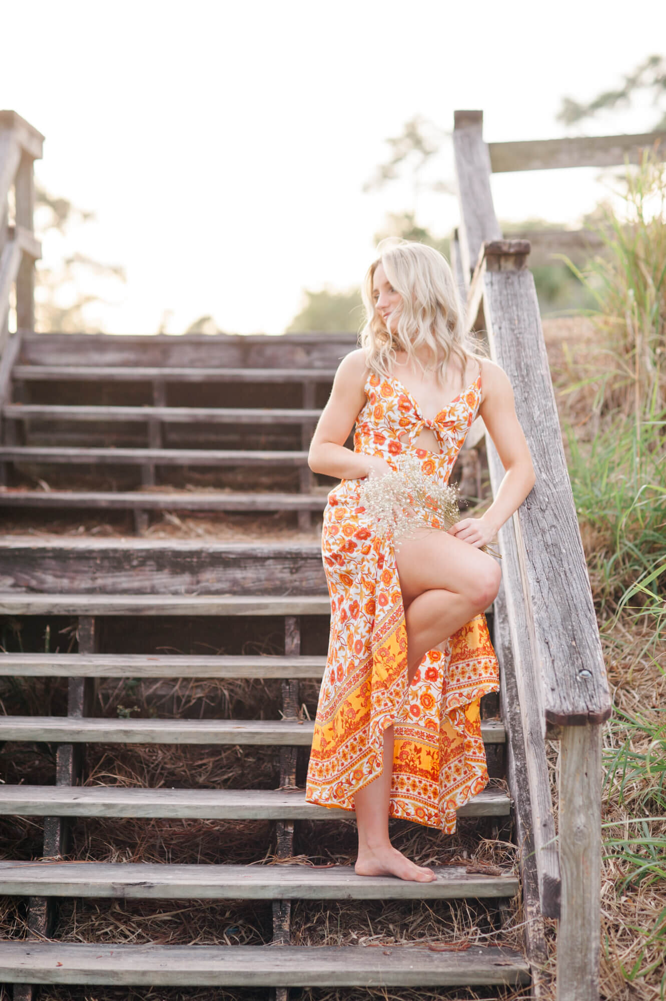 Senior dance girl stands in a dance pose on a wooden stair case at a park in Winter Park during her senior photo session