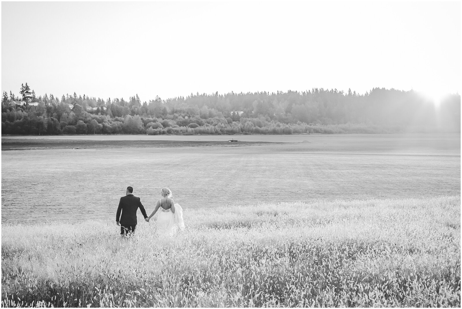 Black and white photo of bride and groom standing in a field