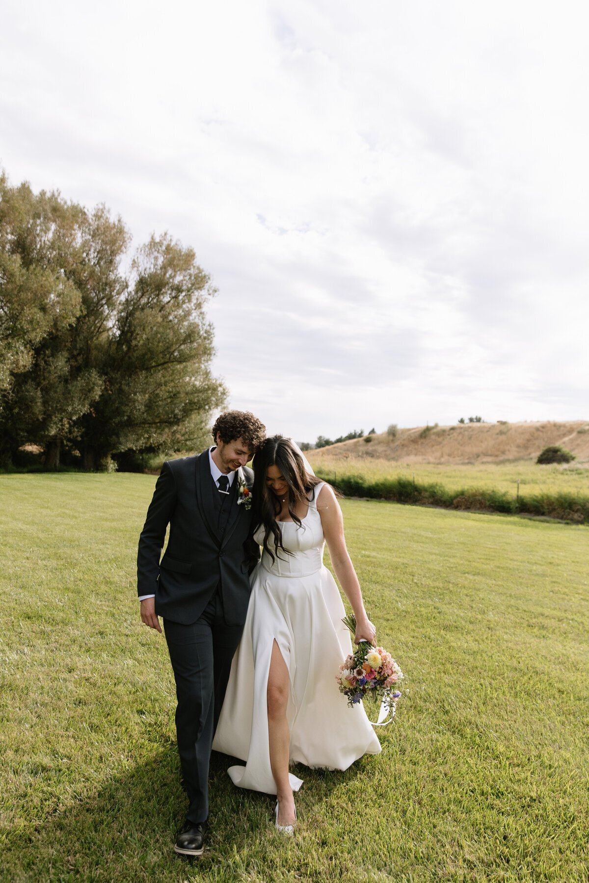 Bride and groom walking on grass by destination wedding photographer