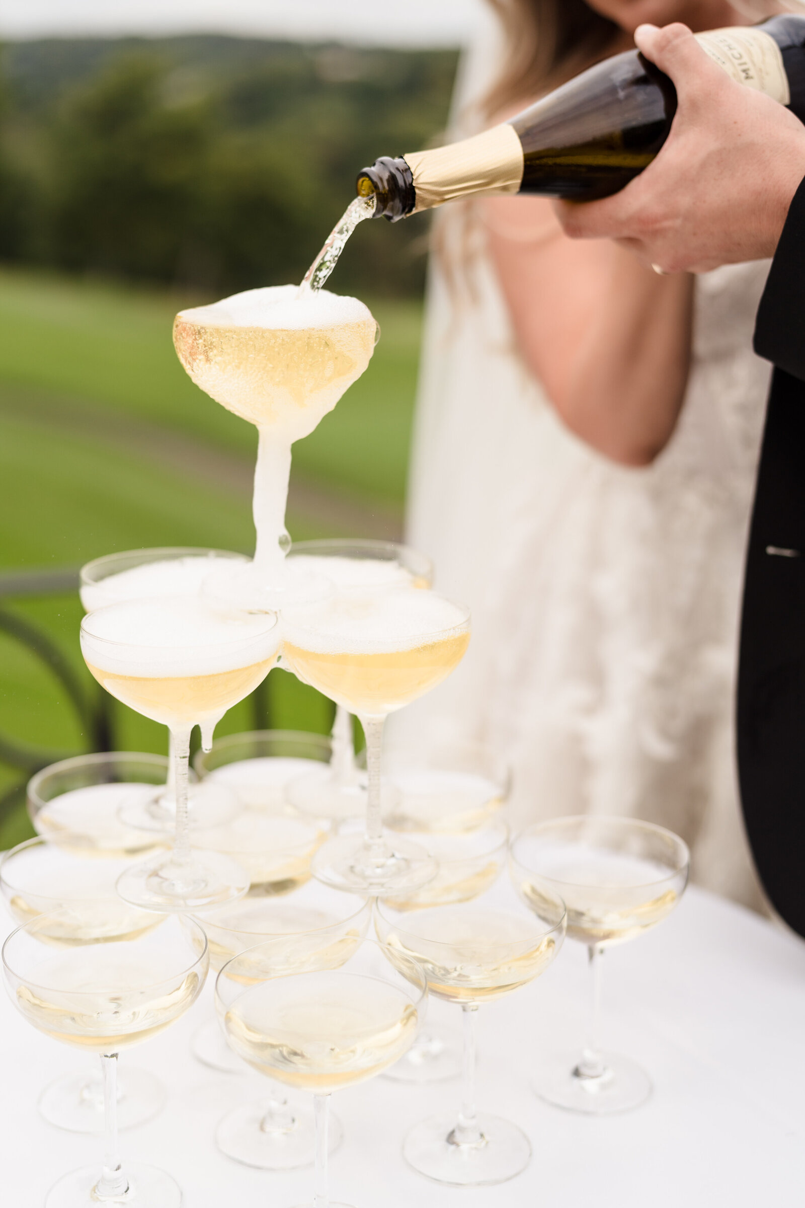 Bride and groom pour champagne into the glasses of their champagne tower