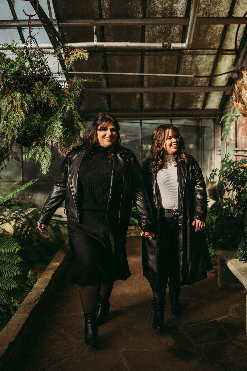 Engaged couple walks in greenhouse wearing all black