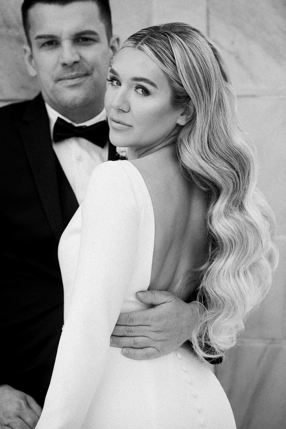 bride look over shoulder with groom in background
