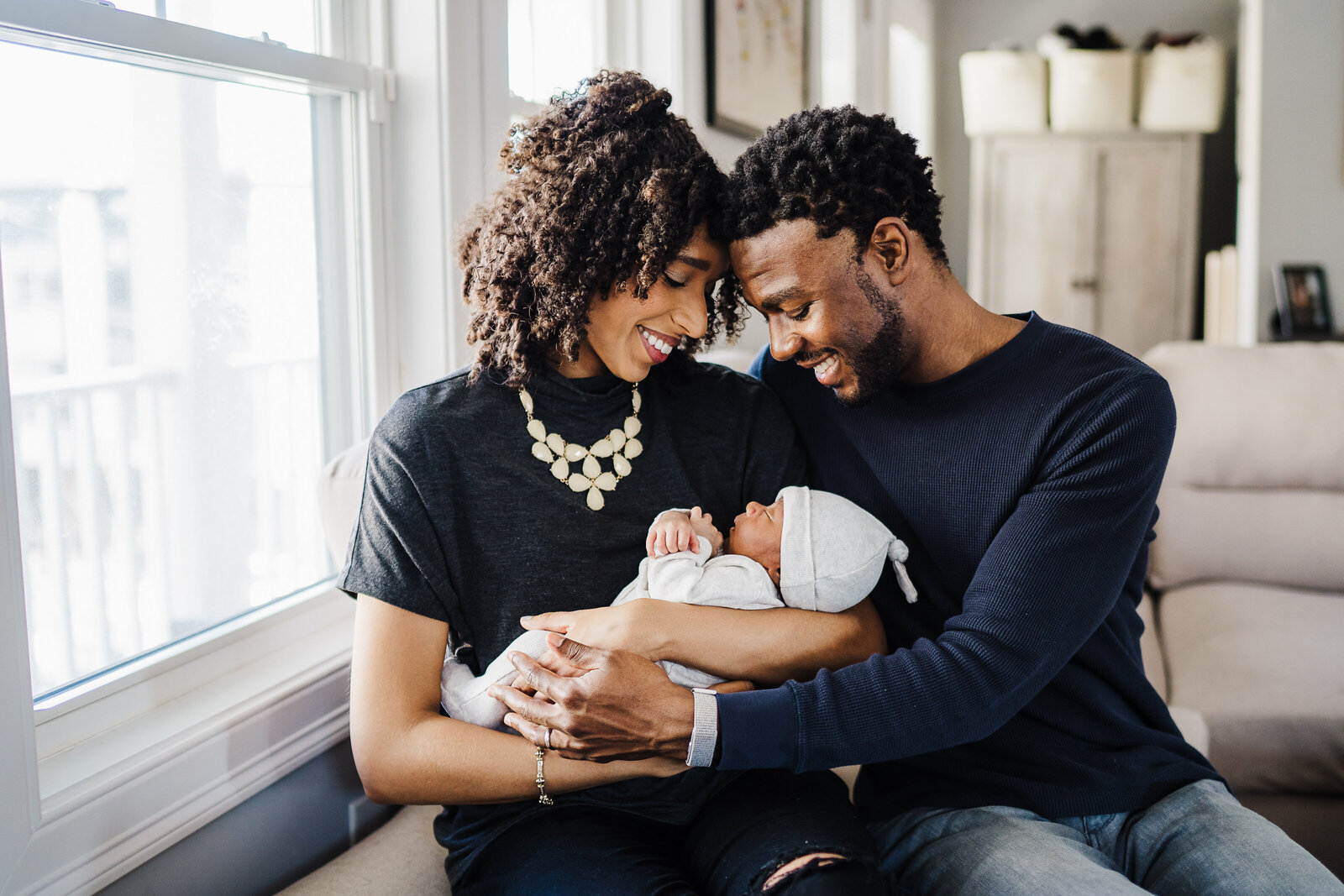 parents dressed in black hold baby boy in family room