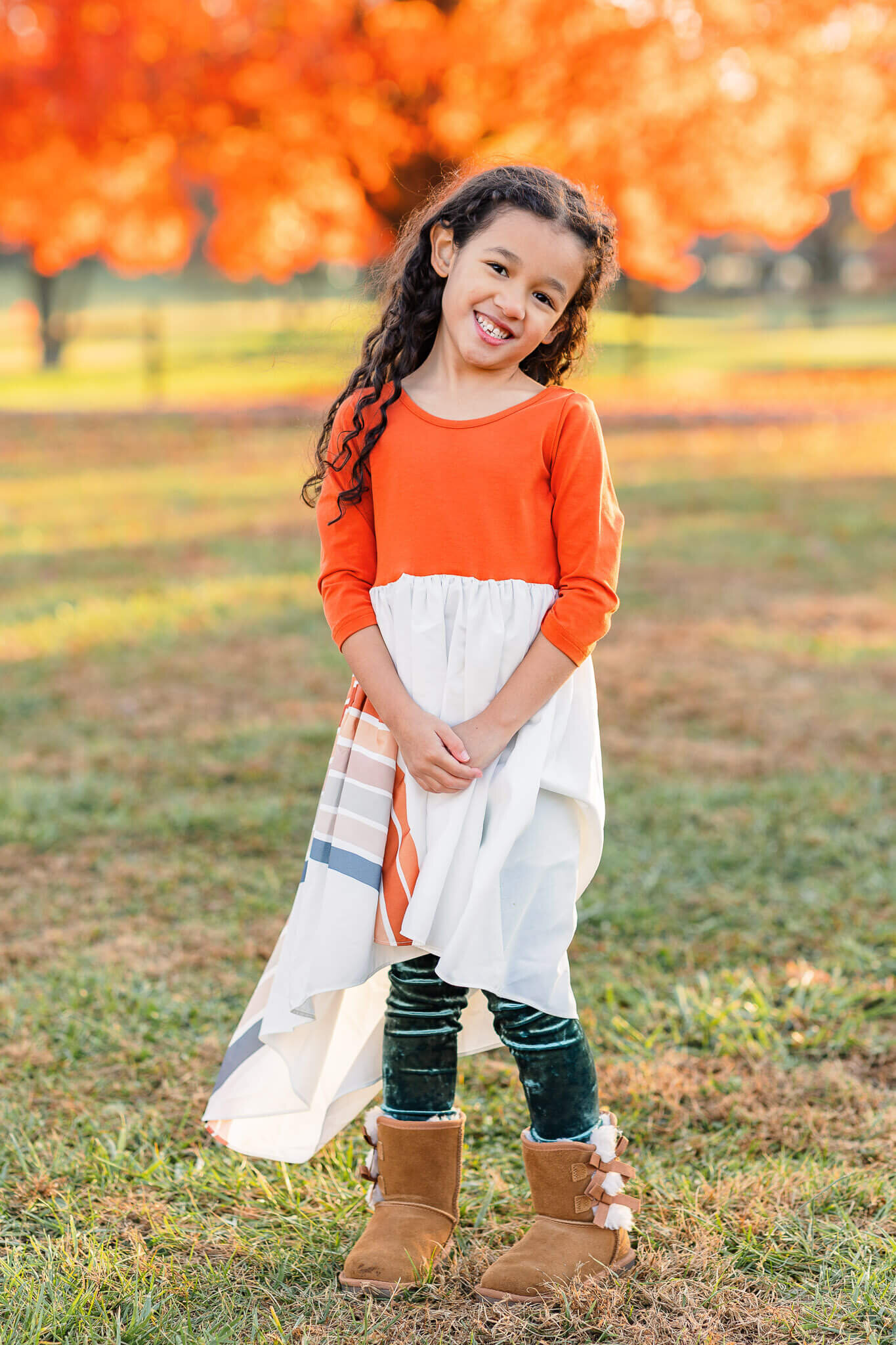 A little girl in a dress posing among fall foliage