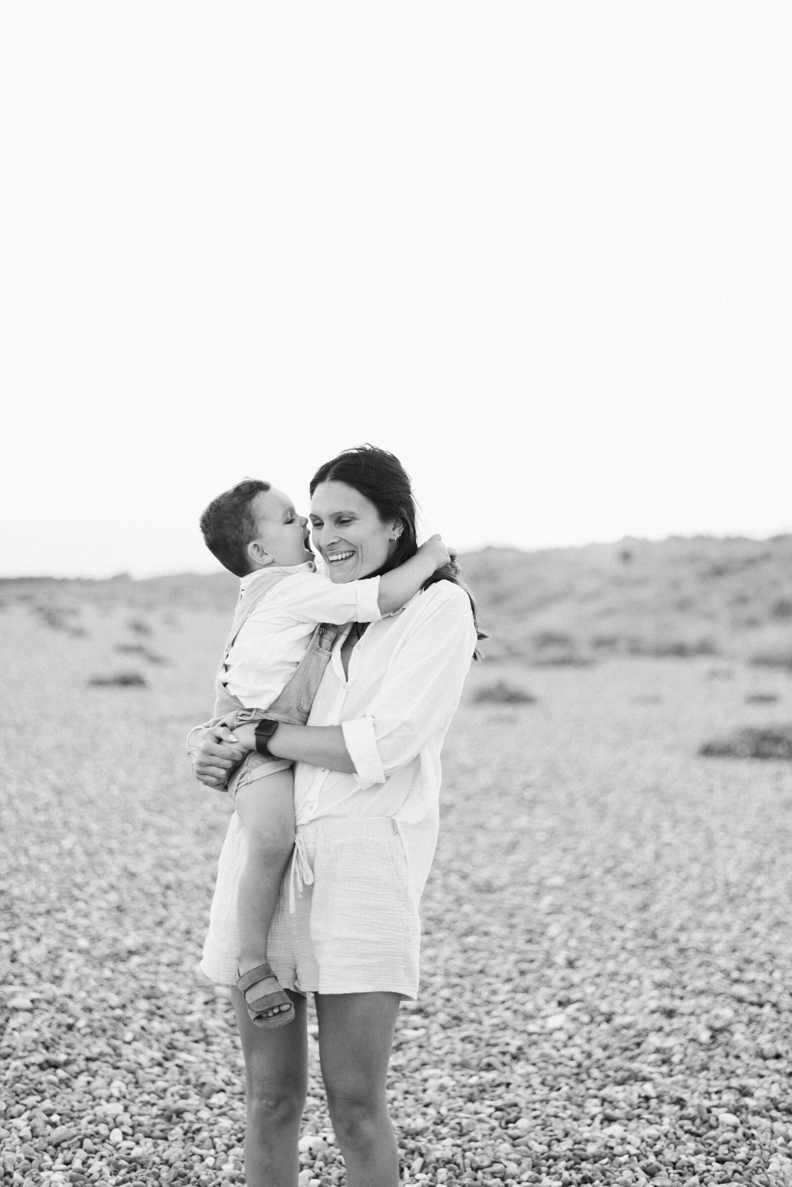 mum holding son on the pebbled beach at family photoshoot in Billingshurst