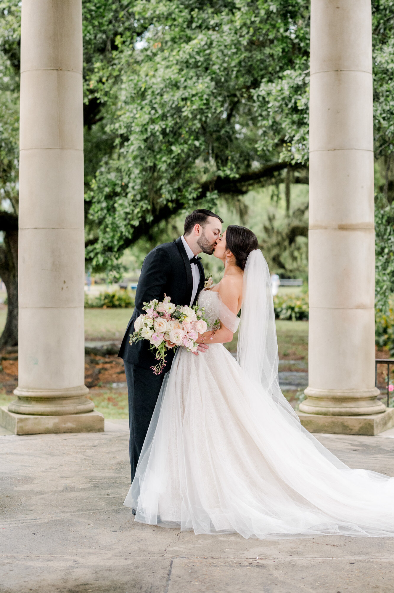 bride and groom kissing next to pillars