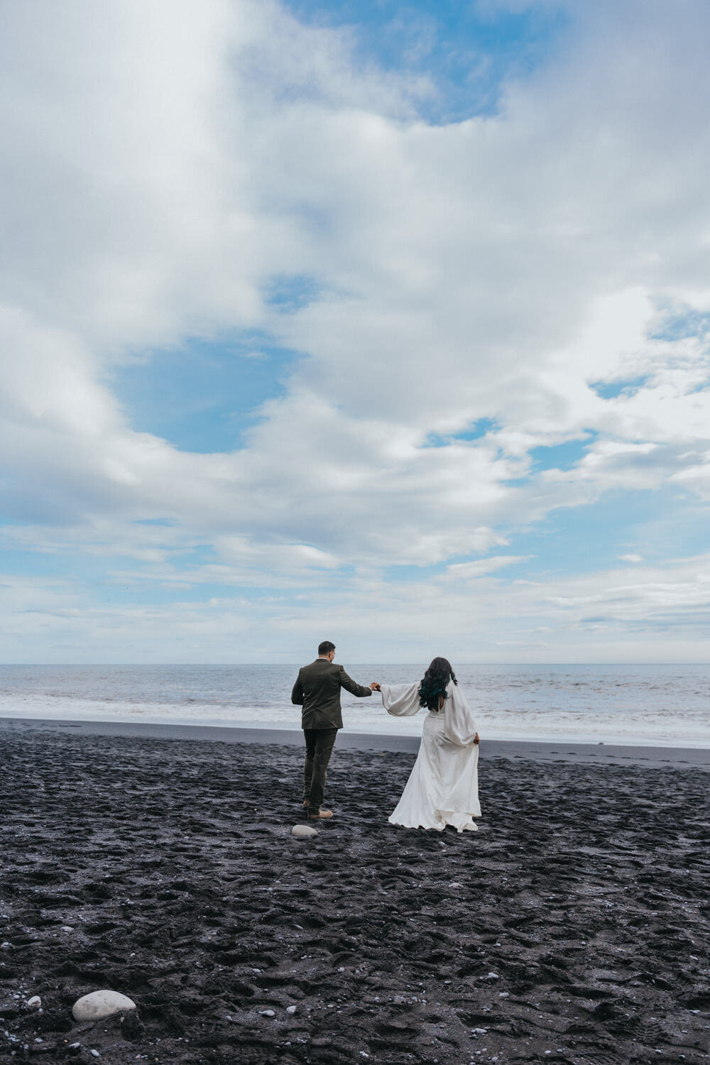 Husband and wife hold hands as they walk down the Black Sand Beaches