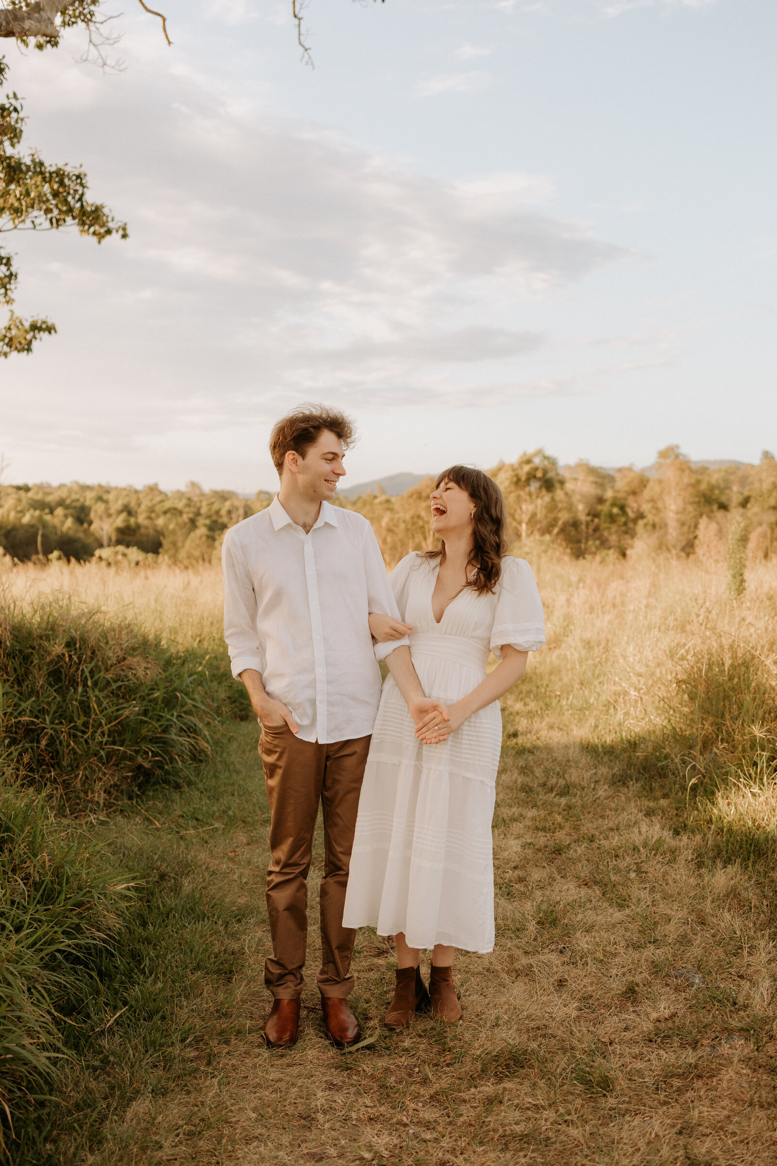 couple holding hands in long grassy field