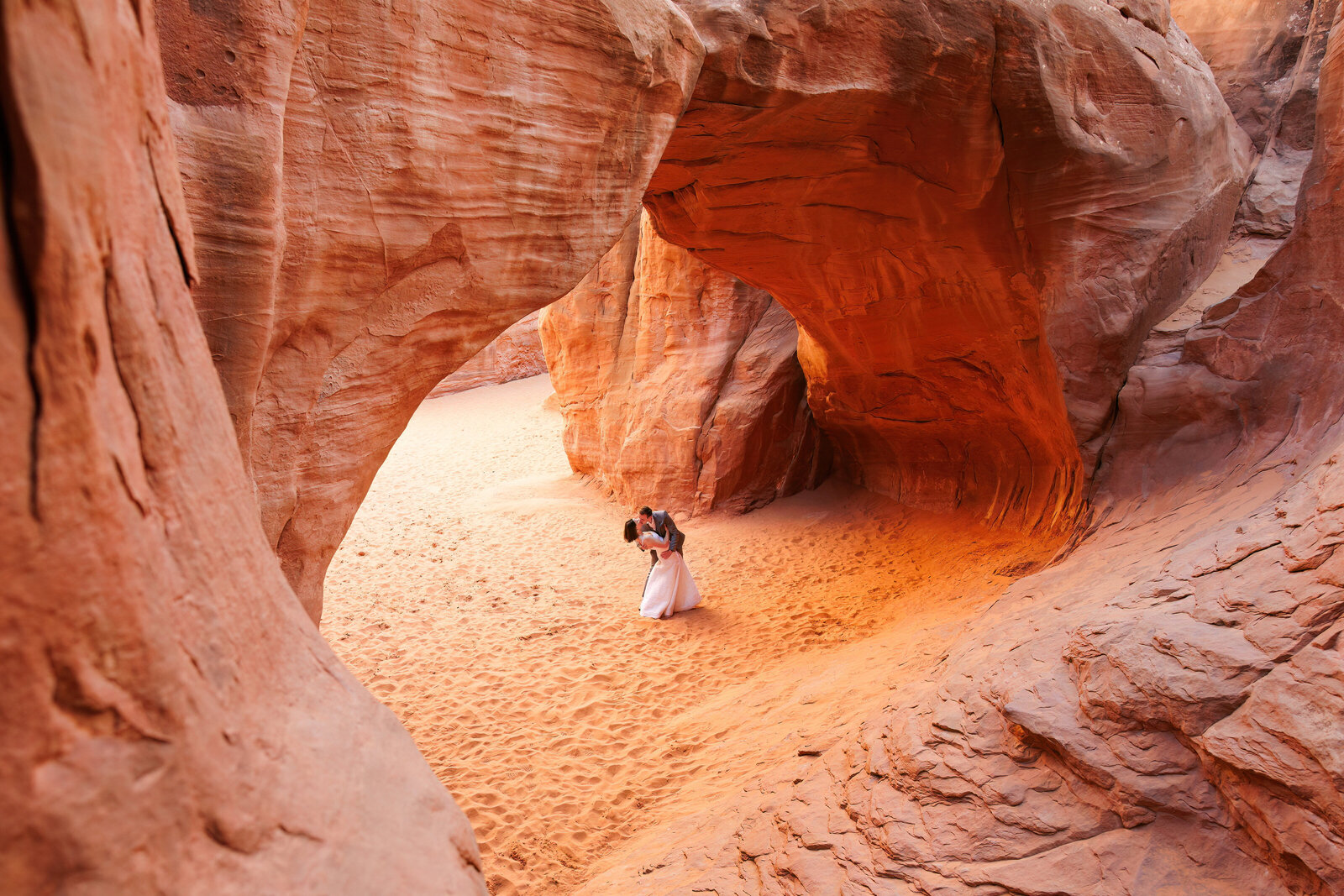 an eloping couple kisses under a stone arch in Arches National Park