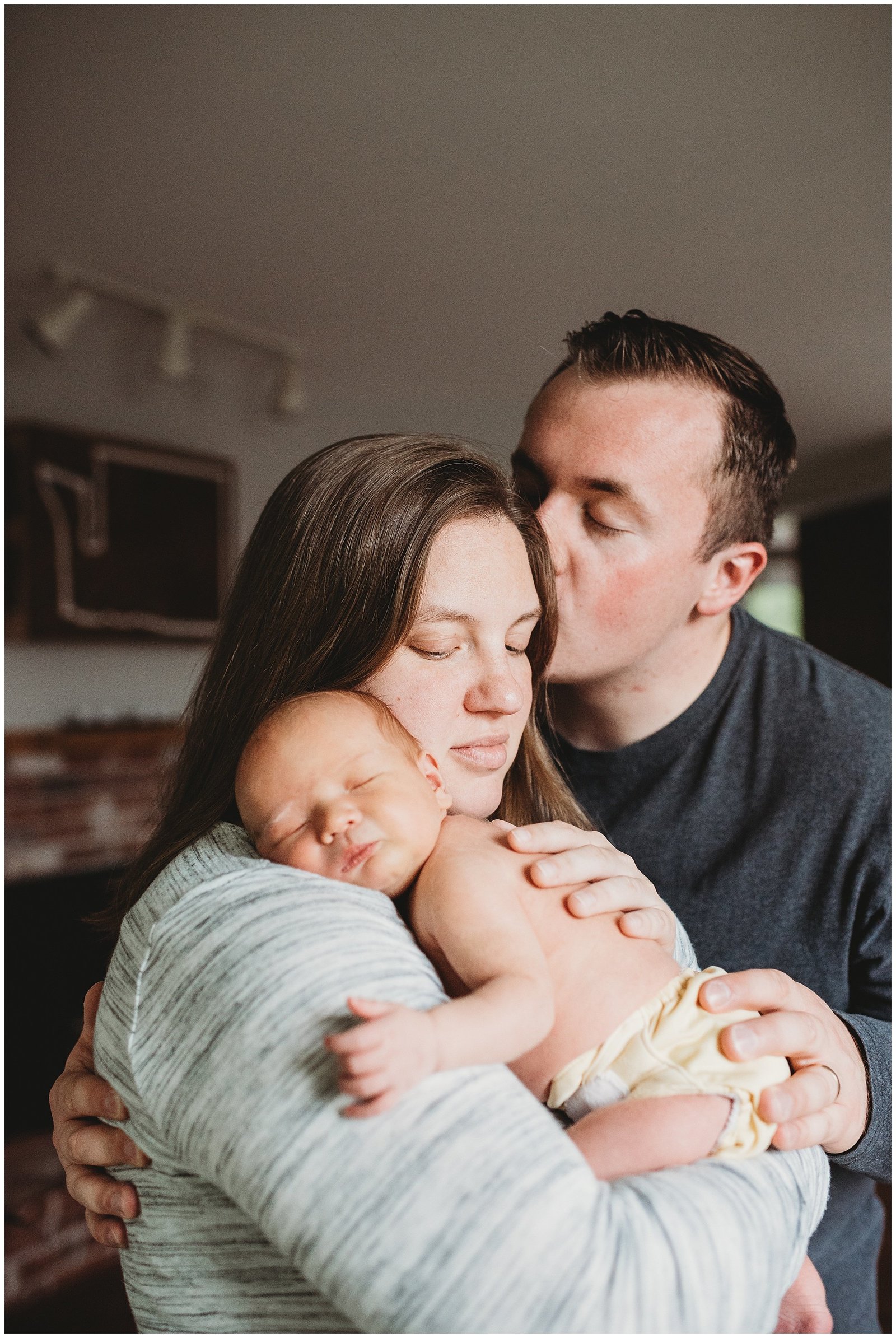 dad kissing mom holding newborn baby boy in home lifestyle photoshoot Emily Ann Photography Seattle Photographer