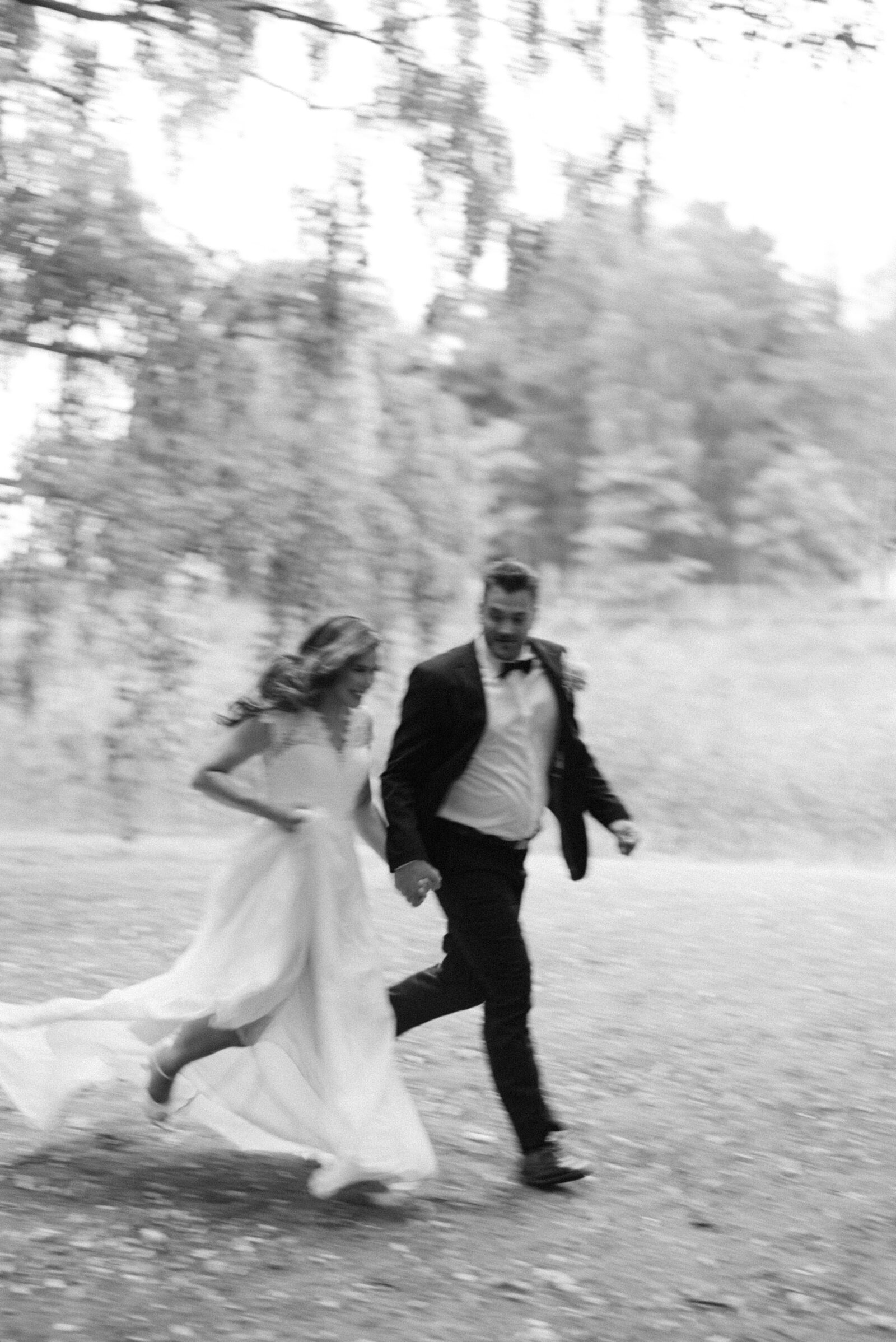 Bride running in her wedding dress and high heels  and holding hands with the groom during their wedding photography session with photographer Hannika Gabrielsson.
