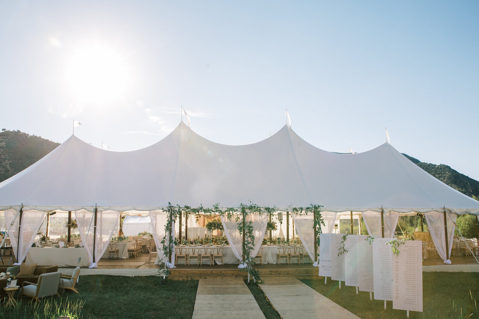 couple standing under huppah wrapped in blue and white striped blanket with white flowers