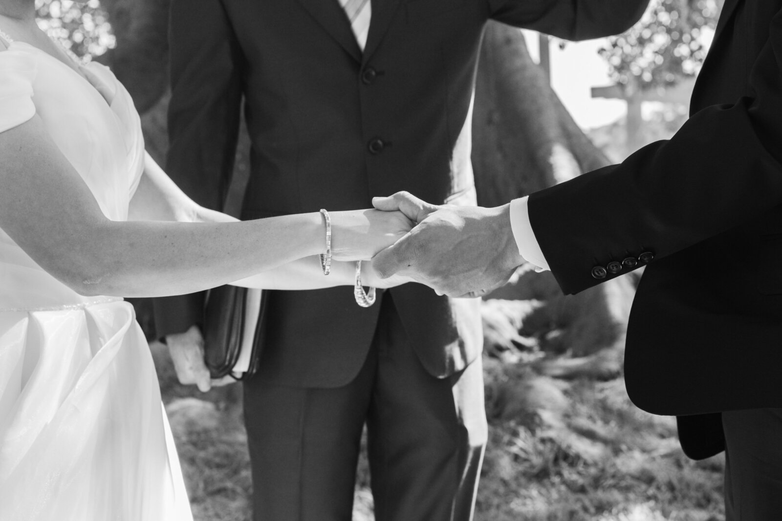 A bride and groom hold hands during their wedding ceremony.