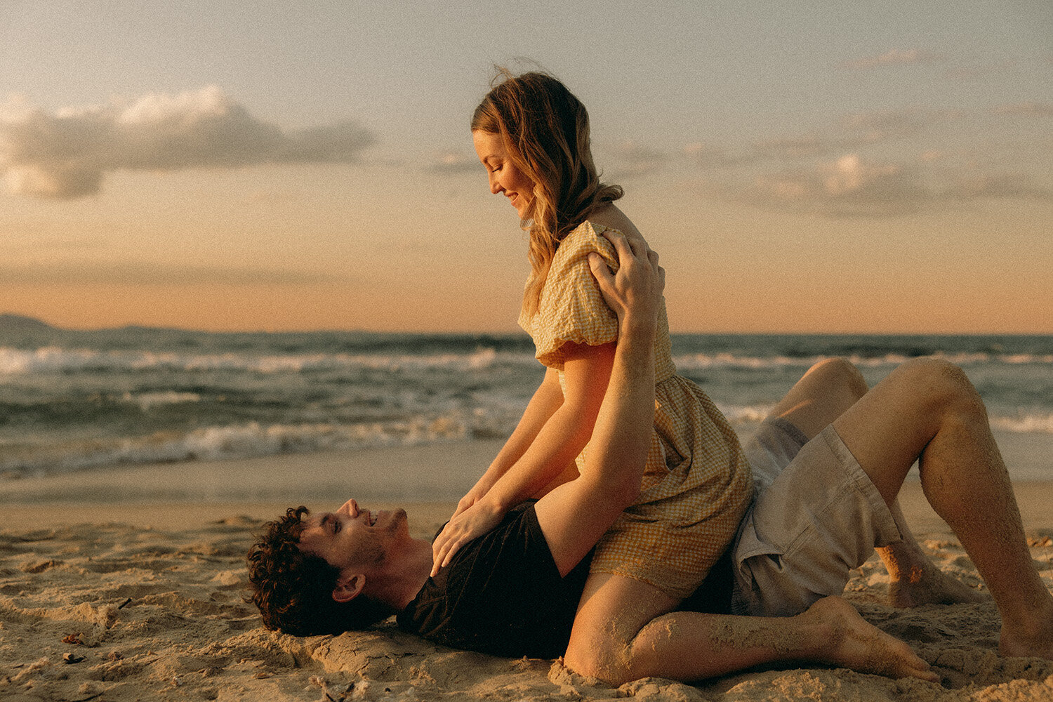 Intimate couple laughing together on the beach at sunset captured by a Sunshine Coast photographer