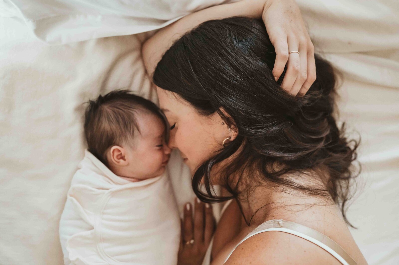 Happy Pittsburgh mother cuddling newborn at home during lifestyle newborn photo session.