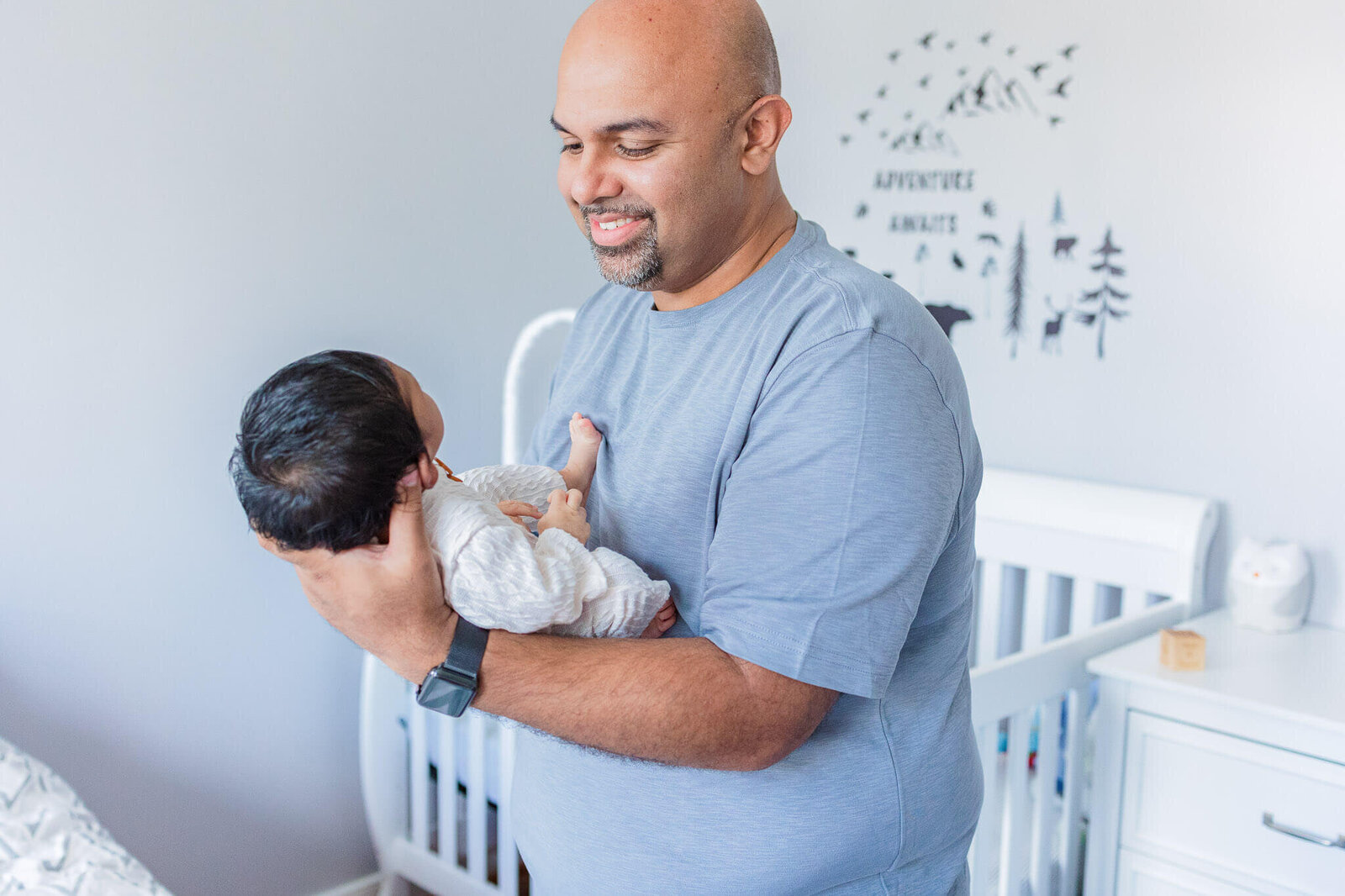 A dad holding his newborn son and smiling at him.