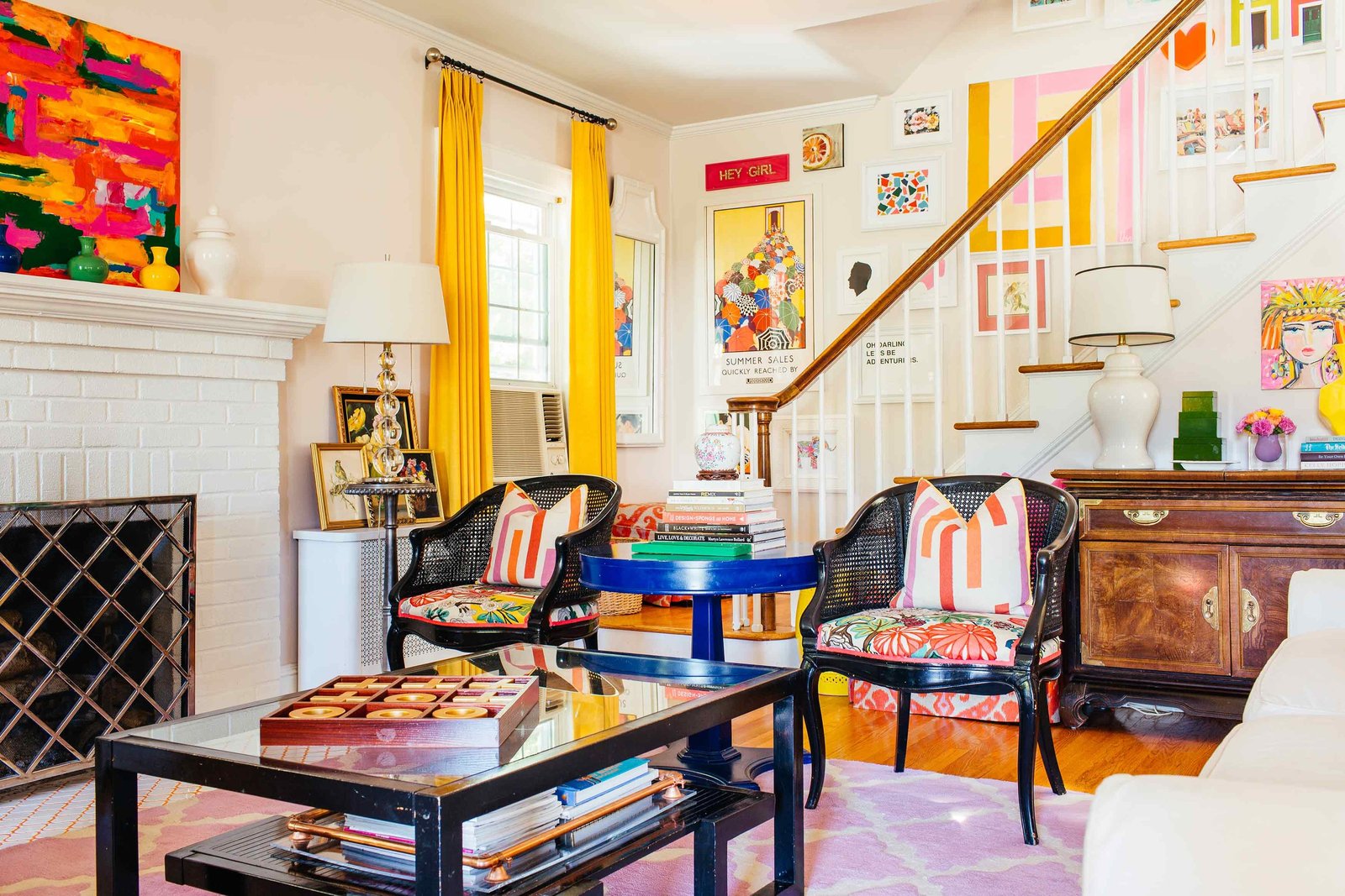 A bright and colorful living room with a white fireplace and staircase.