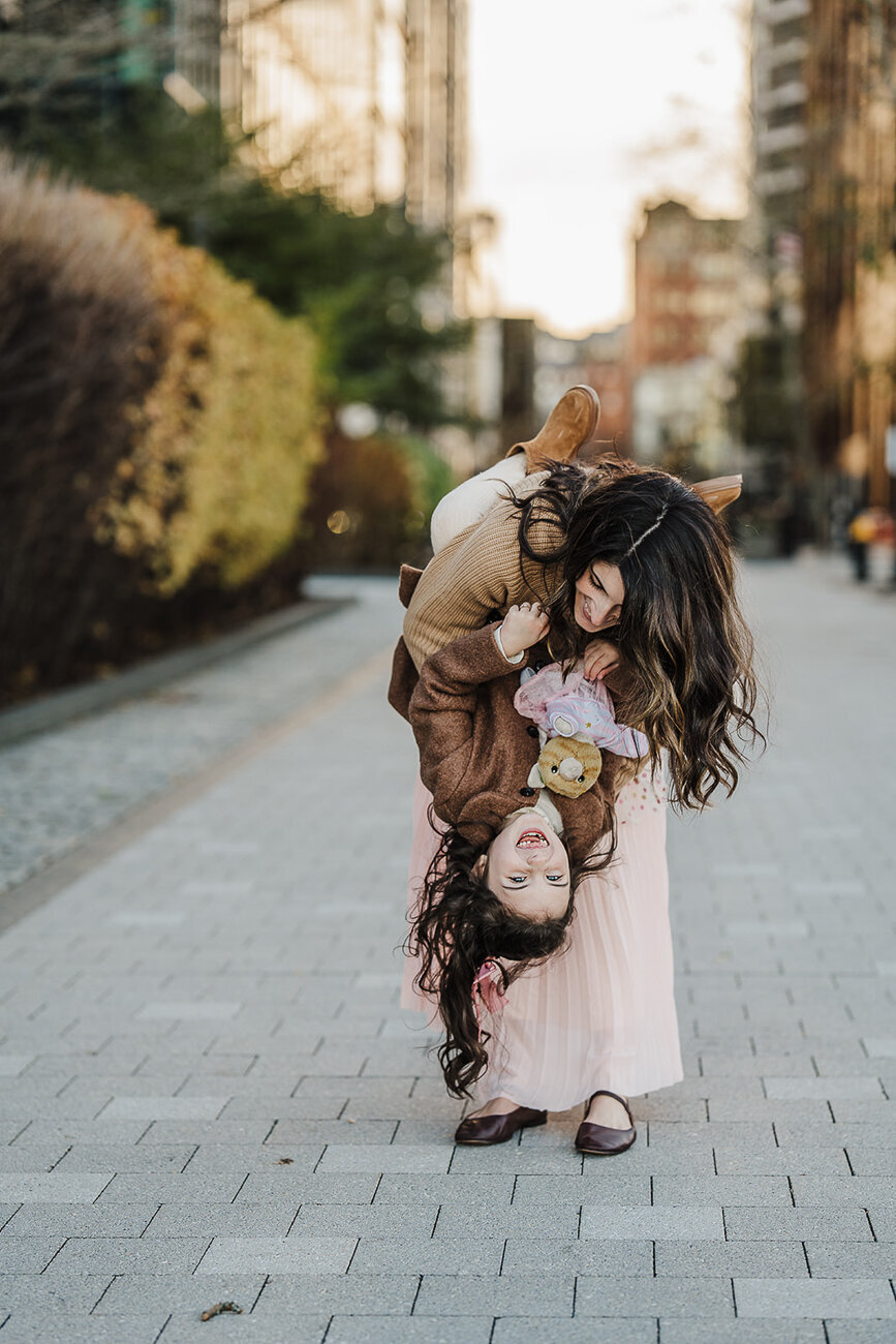 mother tips daughter upside down during boston seaport photo session