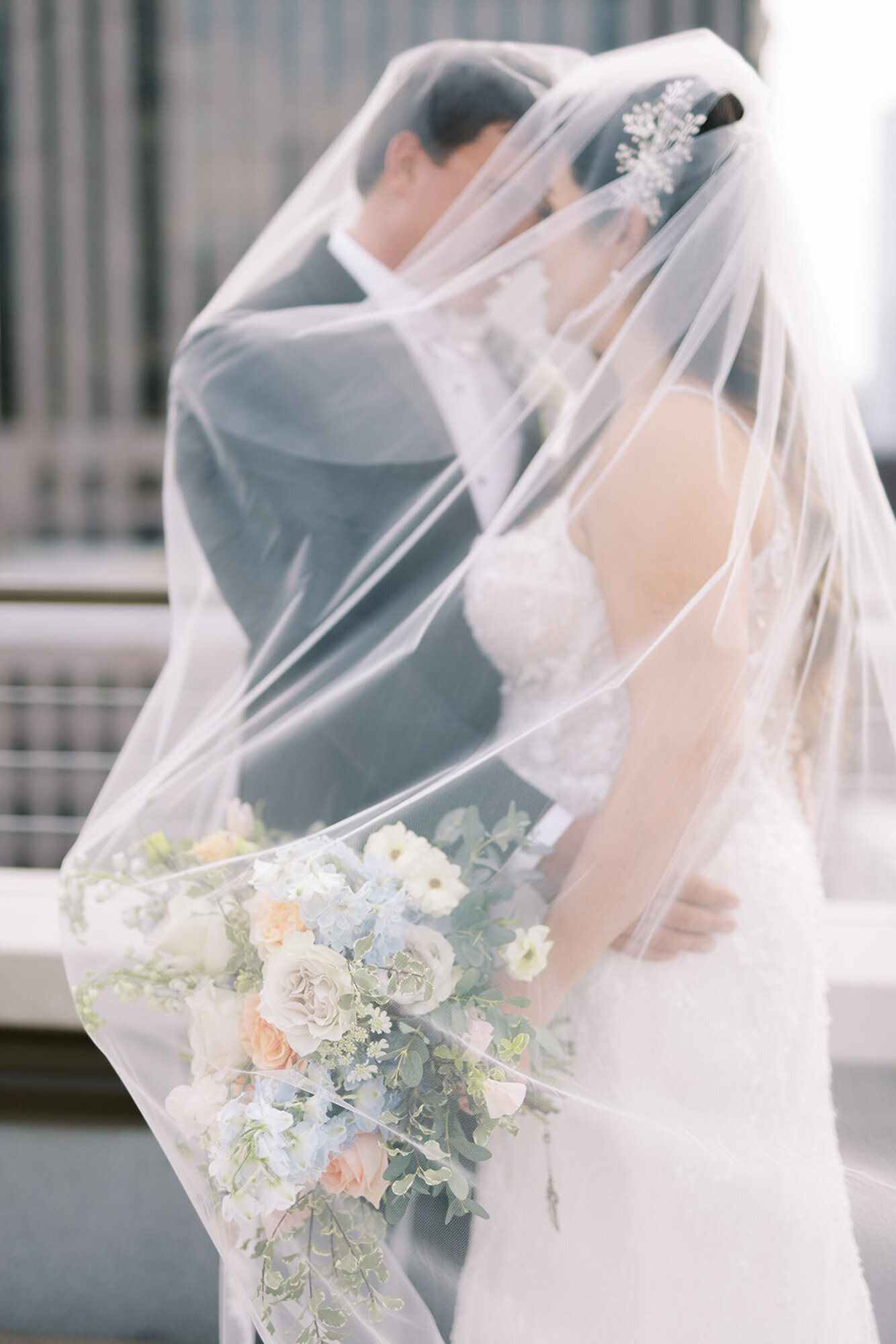 bride and groom standing under wedding veil