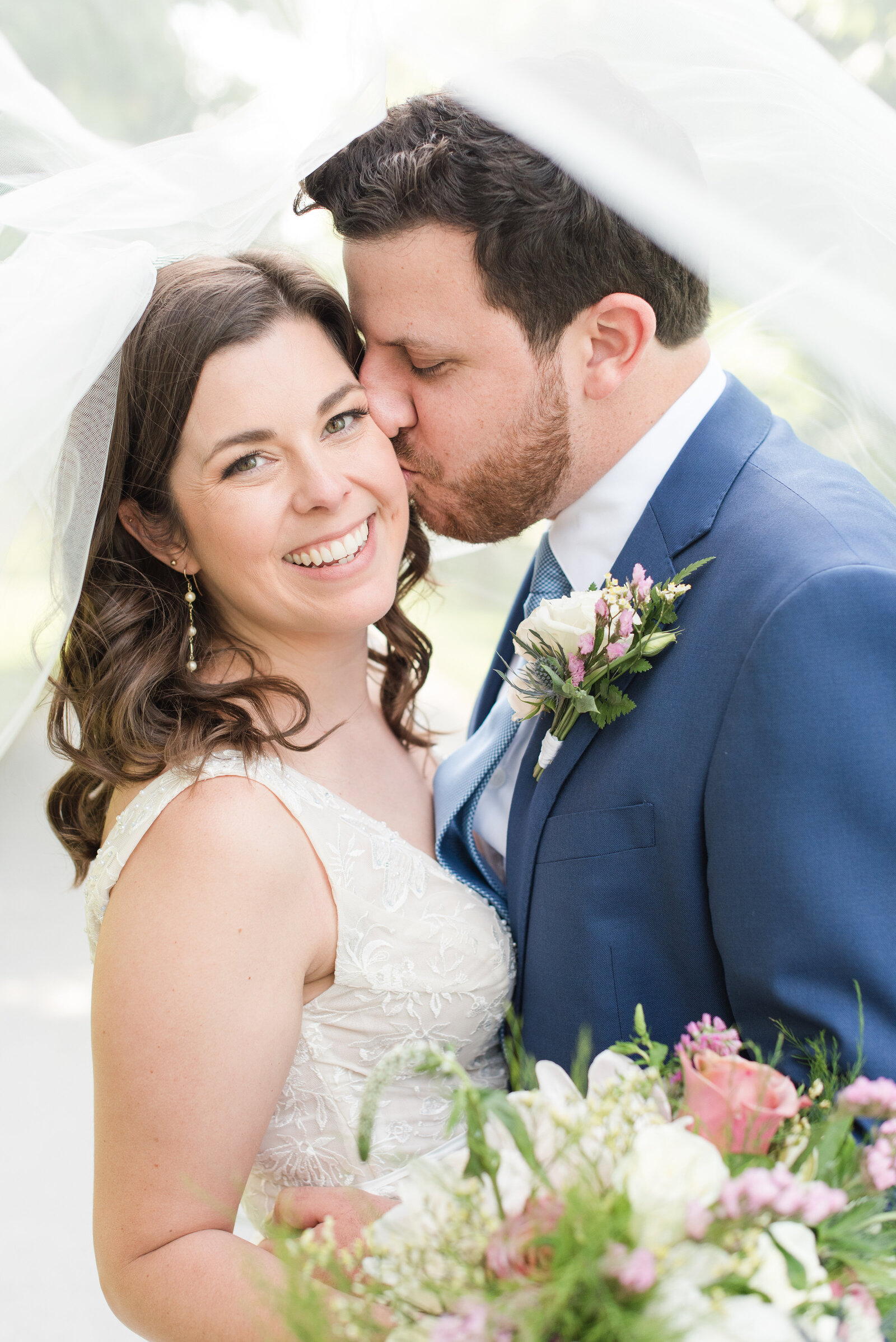groom kissing bride on the cheeks while she smiles